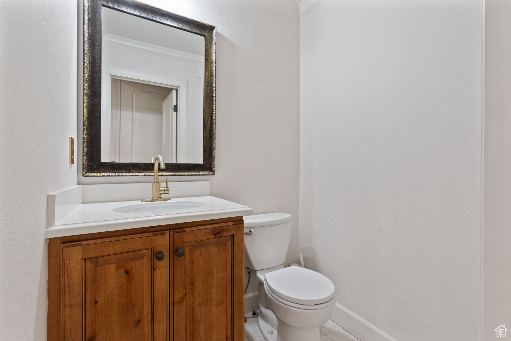 Bathroom with tile flooring, vanity with extensive cabinet space, toilet, and ornamental molding