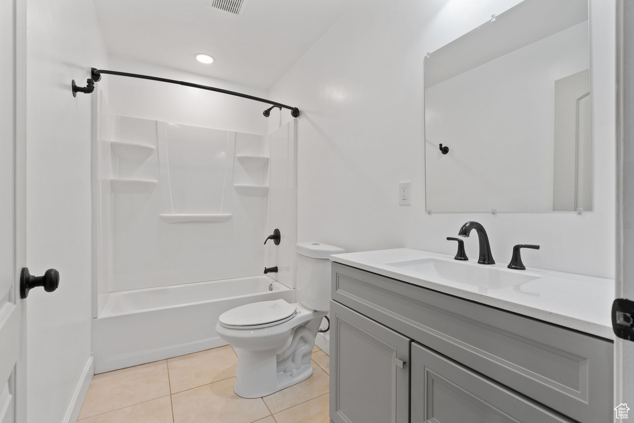 Full bathroom with vanity with extensive cabinet space, toilet, tile floors, and bathing tub / shower combination