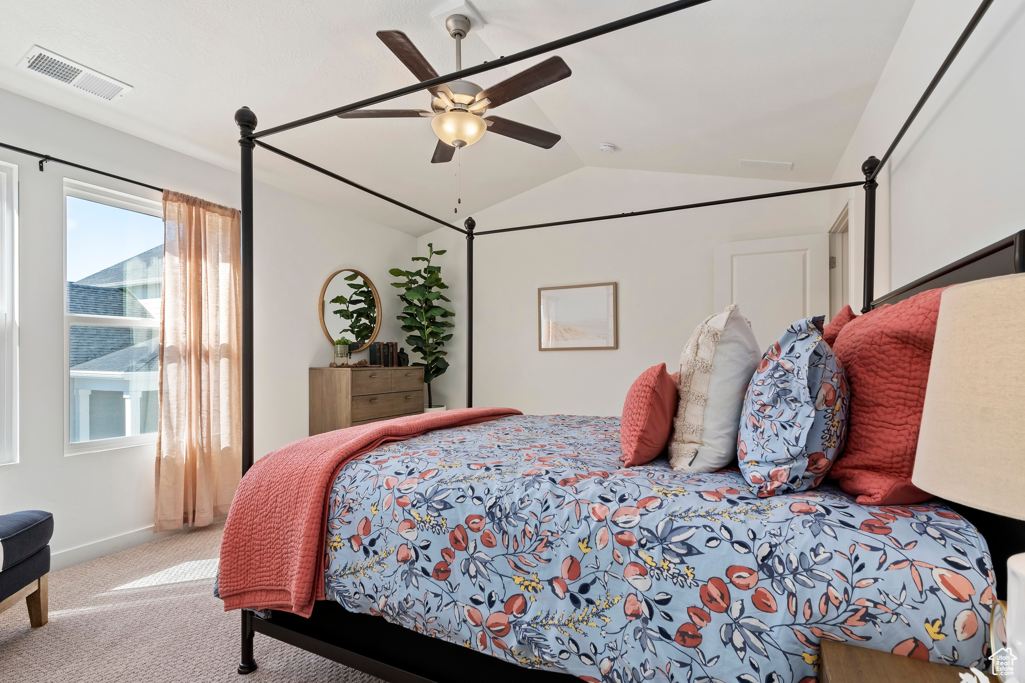 Carpeted bedroom featuring vaulted ceiling, ceiling fan, and multiple windows