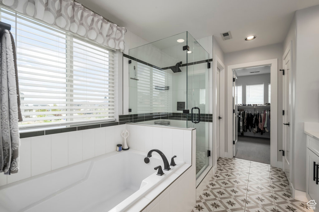 Primary Bathroom with spacious  vanity, separate shower and tub, and tile floors