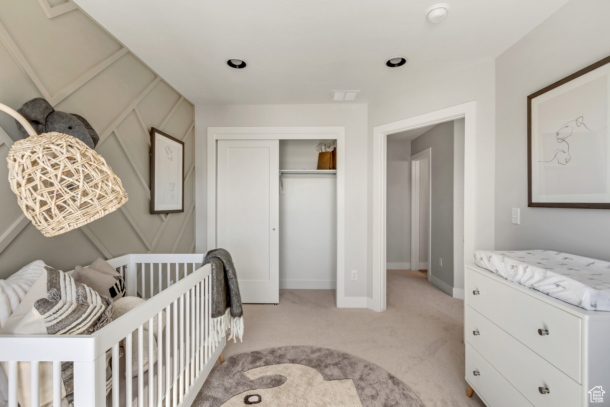 Bedroom featuring light colored carpet, a closet, and a crib