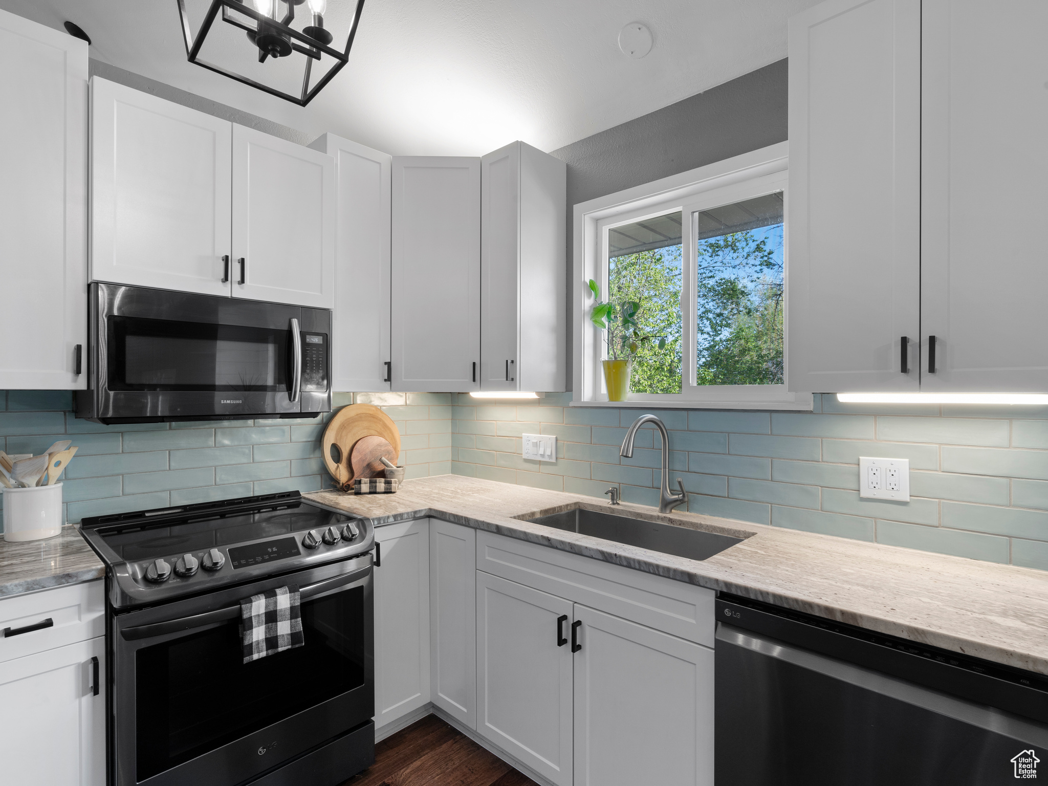 Kitchen with sink, backsplash, dark hardwood / wood-style flooring, stainless steel appliances, and light stone countertops