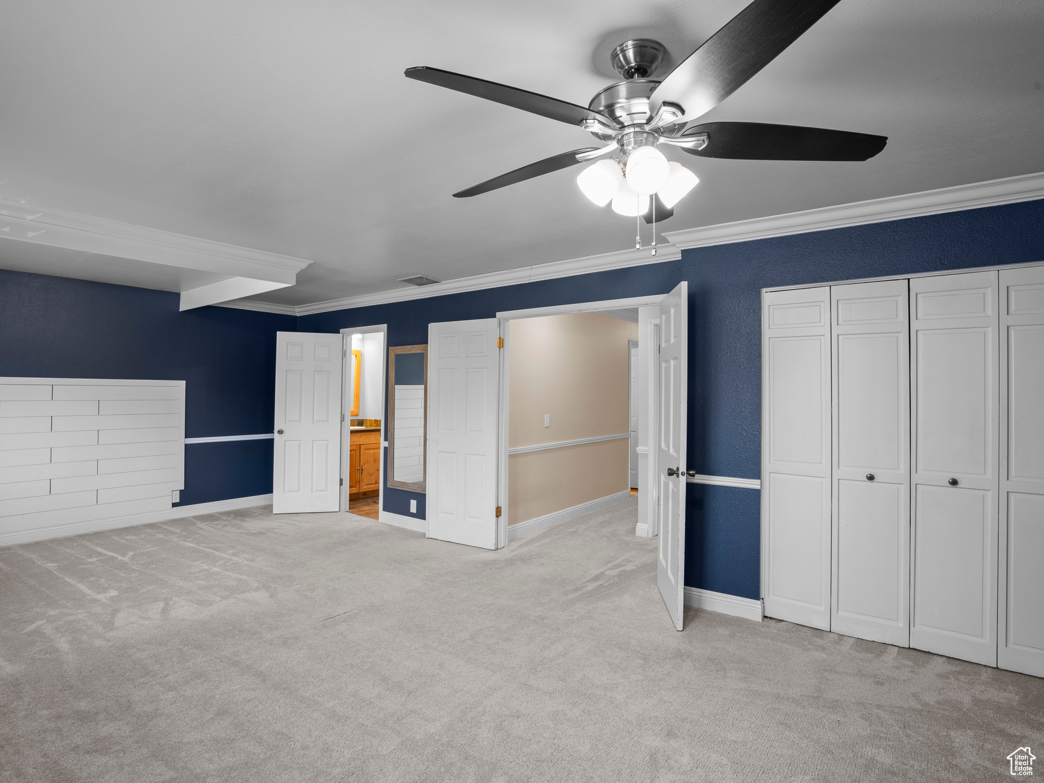 Unfurnished bedroom with light colored carpet, ceiling fan, and ornamental molding