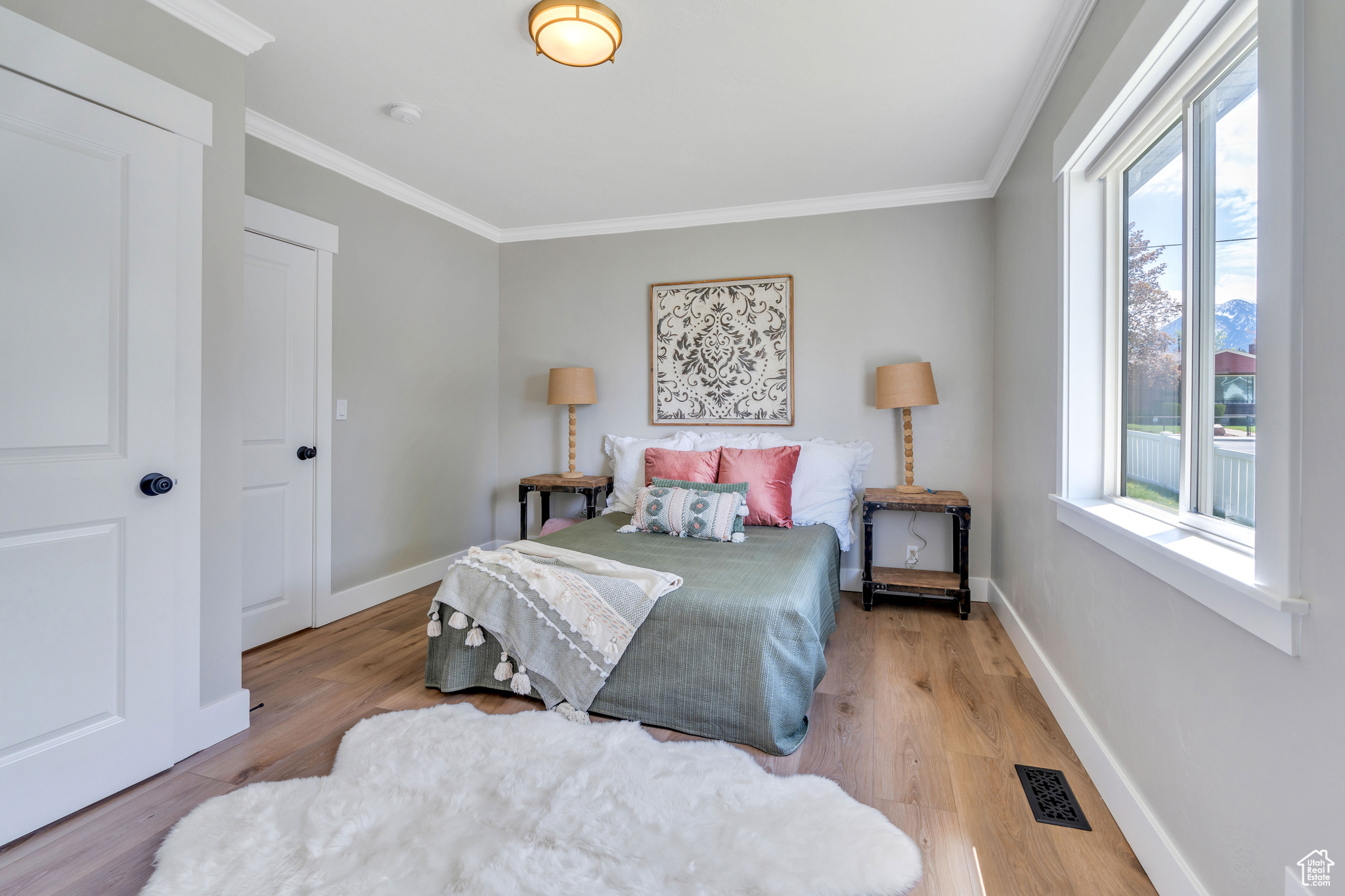 Bedroom featuring crown molding, light hardwood / wood-style floors, and multiple windows