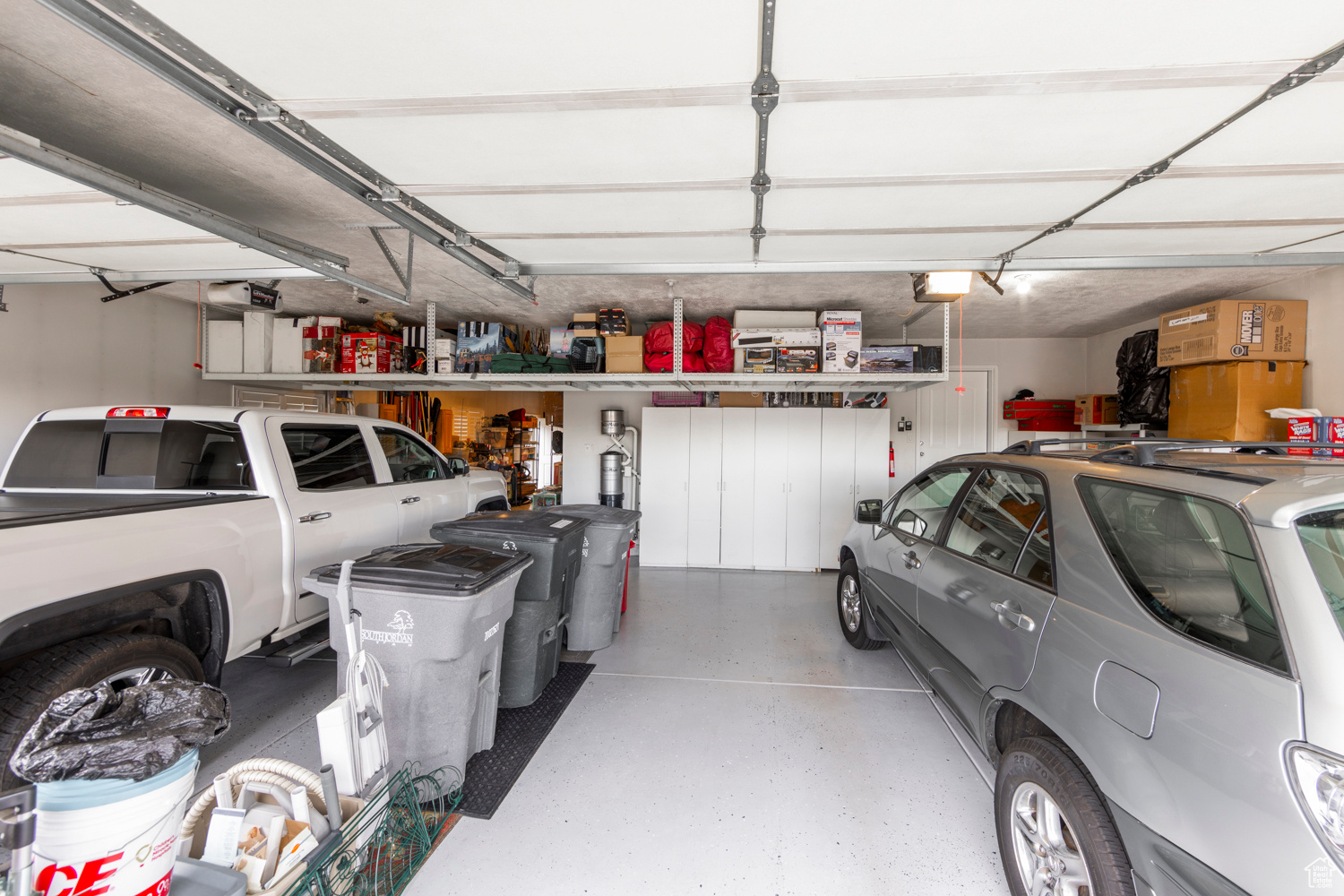 View of garage, with optional overhead hanging shelves and optional cabinets for storage (both to be purchased separately)