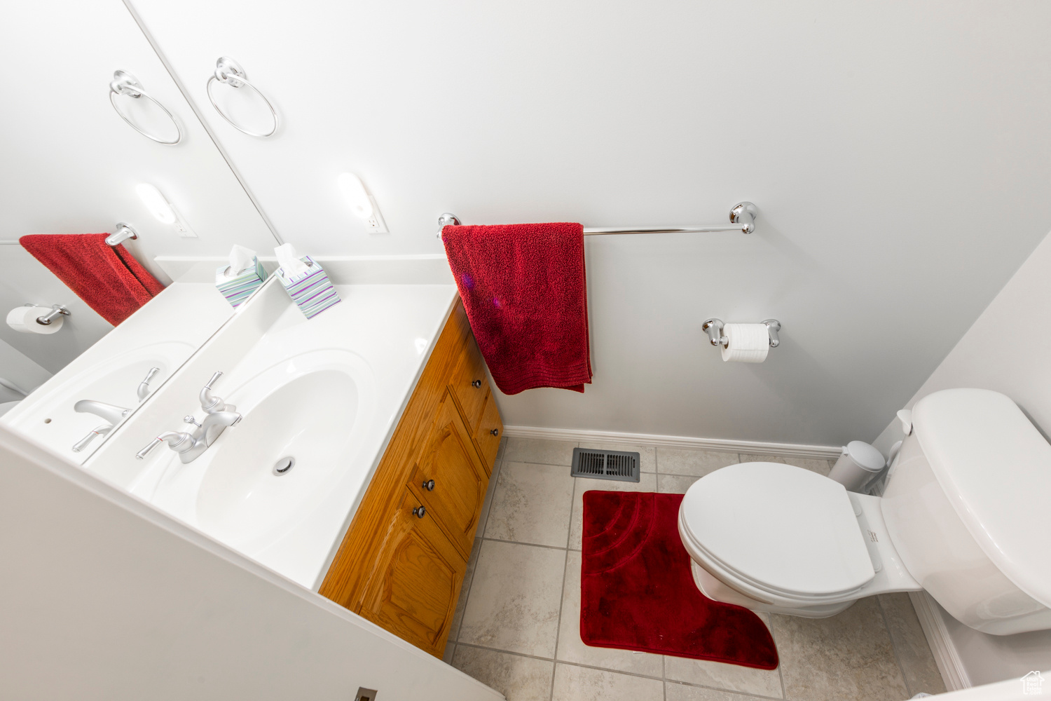 1/2 Bathroom  of of kitchen featuring vanity with extensive cabinet space, tile floors, and toilet