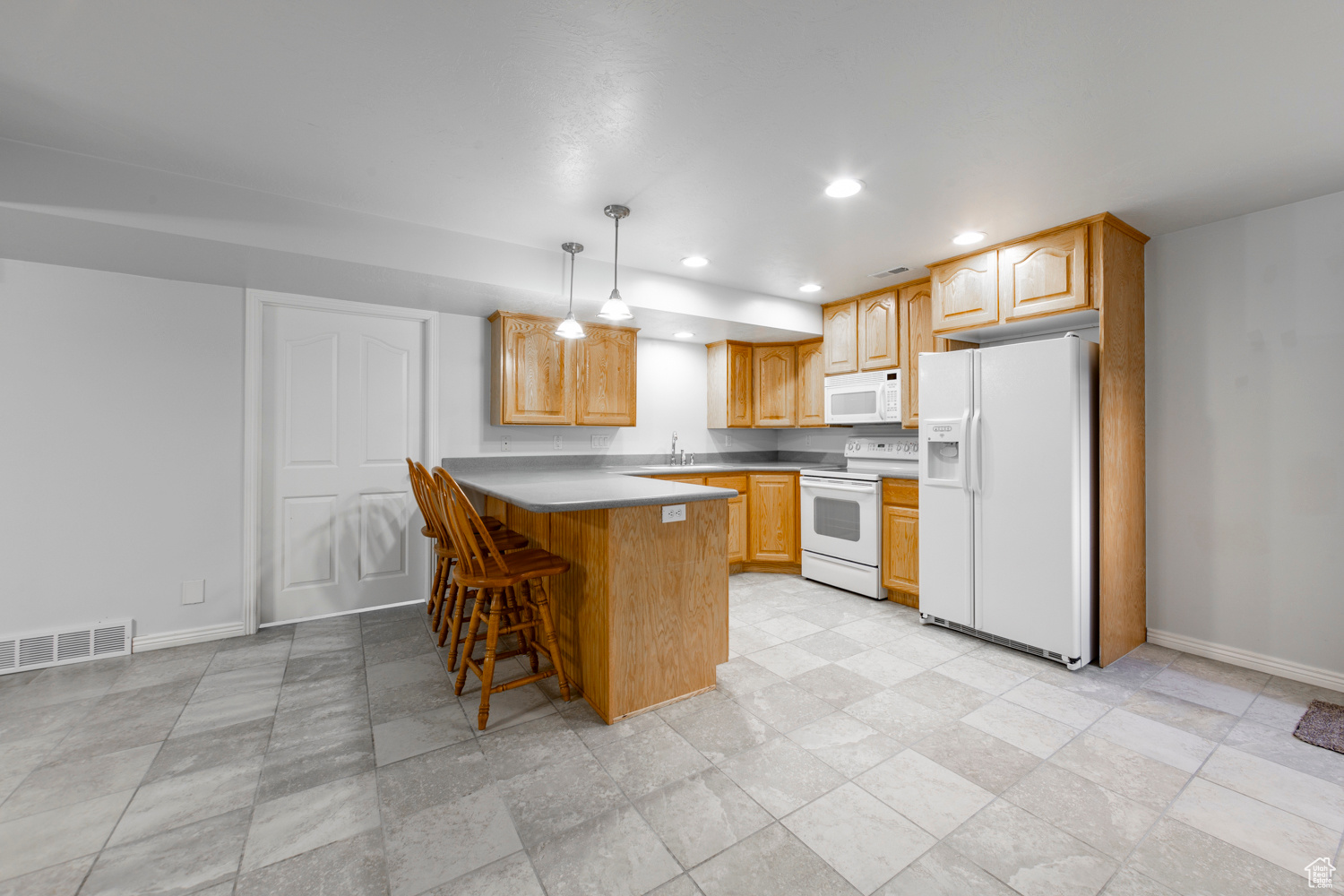 Full Kitchen featuring a kitchen breakfast bar, pendant lighting, white appliances, and light tile floors