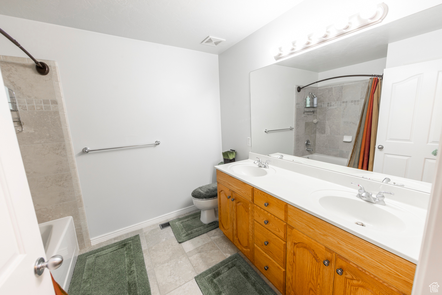 Full bathroom with dual sinks, oversized vanity, shower / tub combo with tile walls, and tile floors