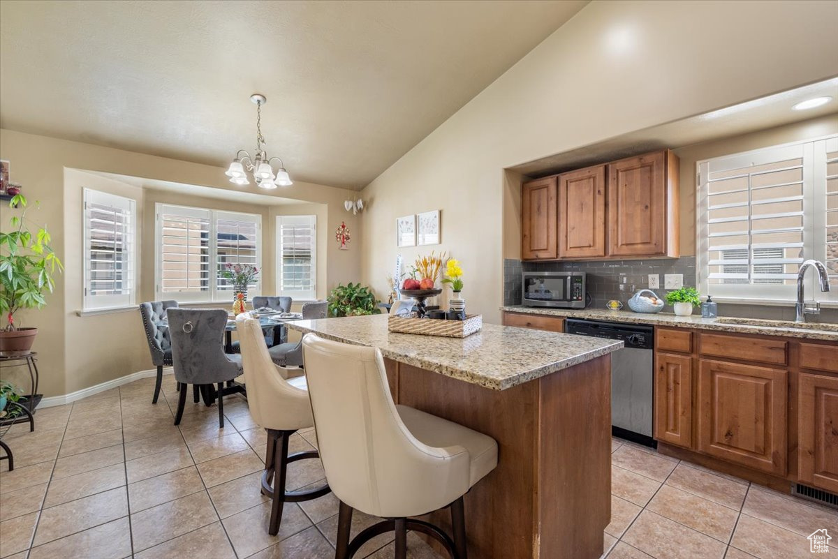 Kitchen with decorative light fixtures, stainless steel appliances, sink, a center island, and light tile floors