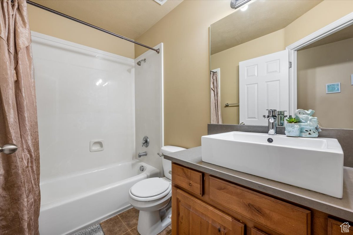 Full bathroom with shower / bathtub combination with curtain, tile floors, toilet, and oversized vanity