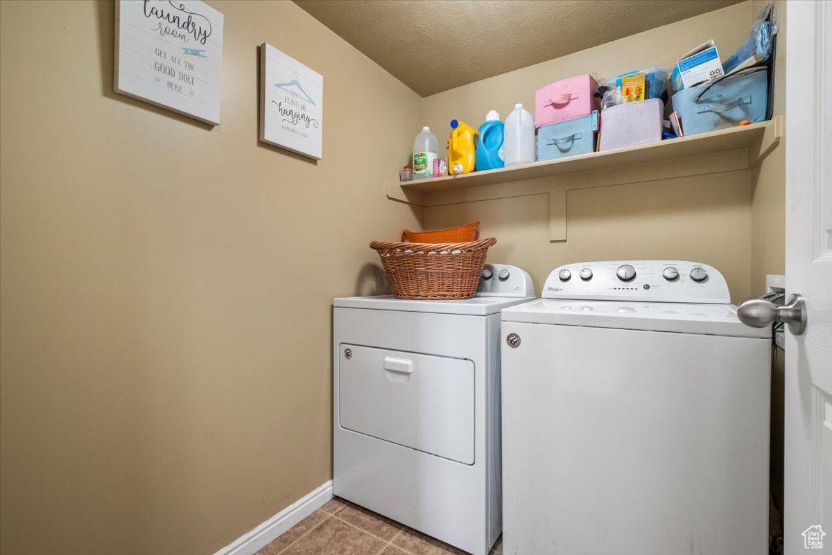 Laundry room with washer and clothes dryer and light tile floors