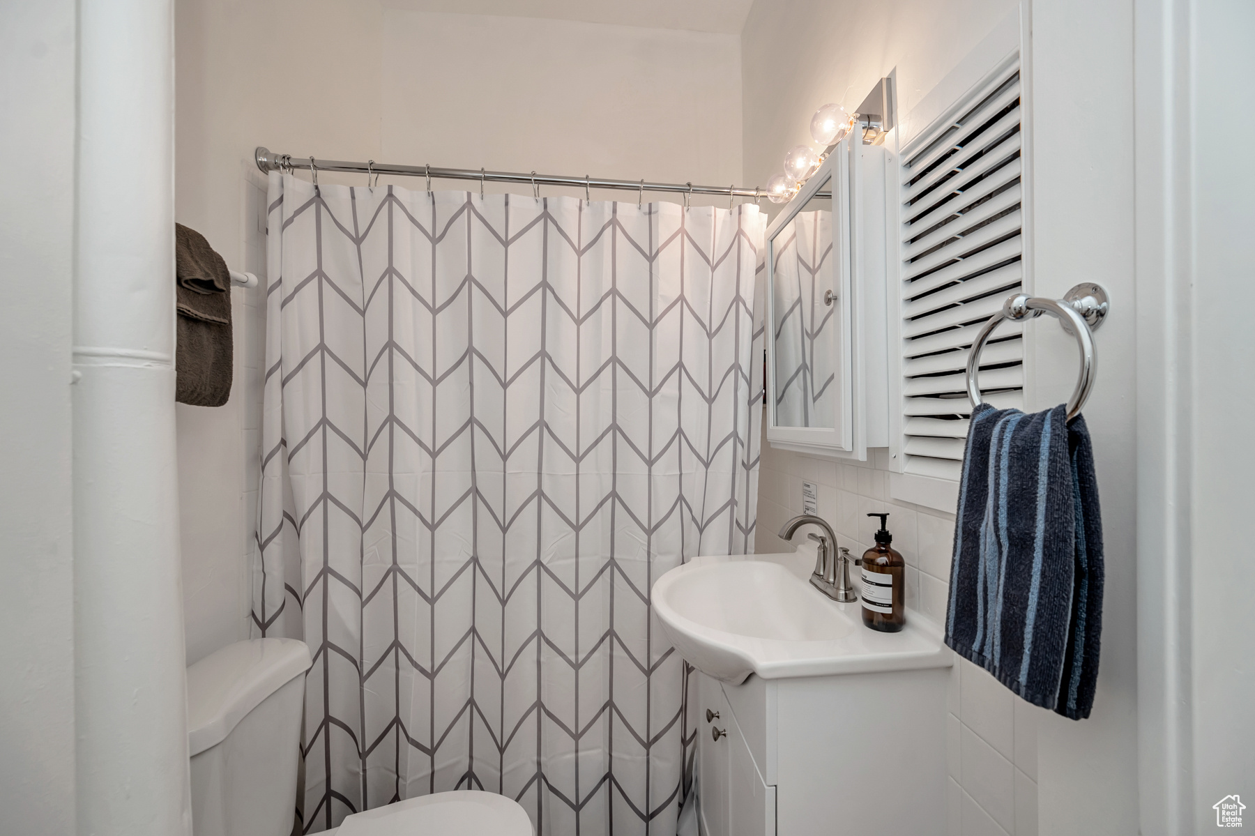 Bathroom featuring tile walls, vanity, and toilet