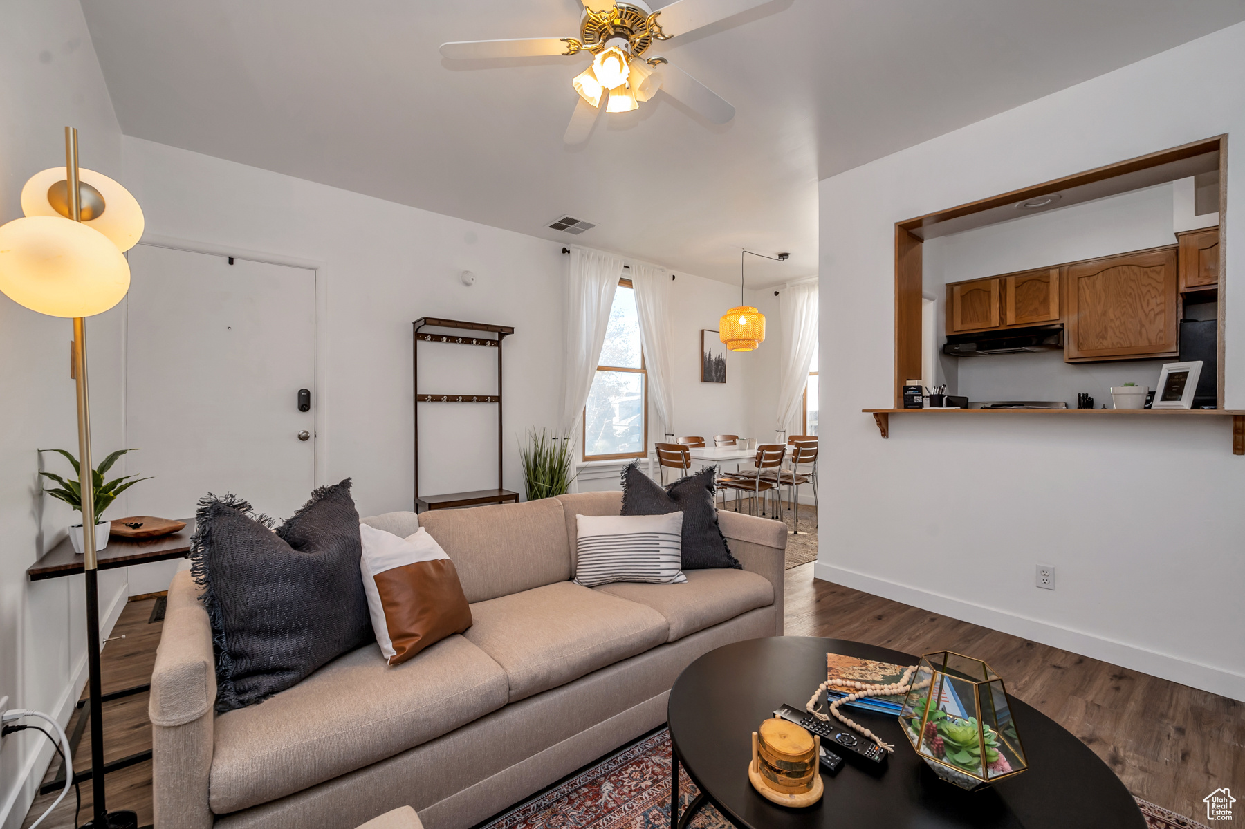 Living room with ceiling fan and dark wood-type flooring