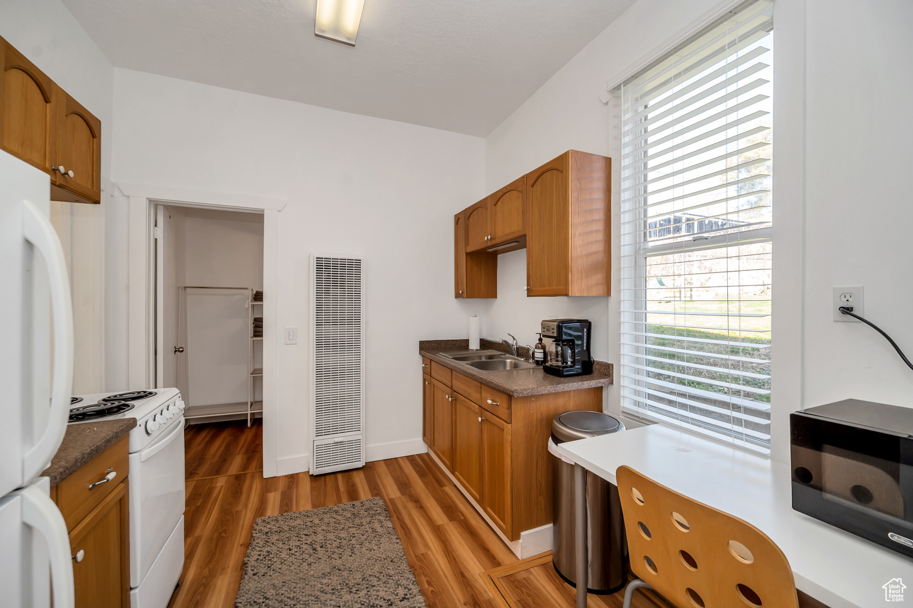 Kitchen with hardwood / wood-style flooring, white appliances, and sink