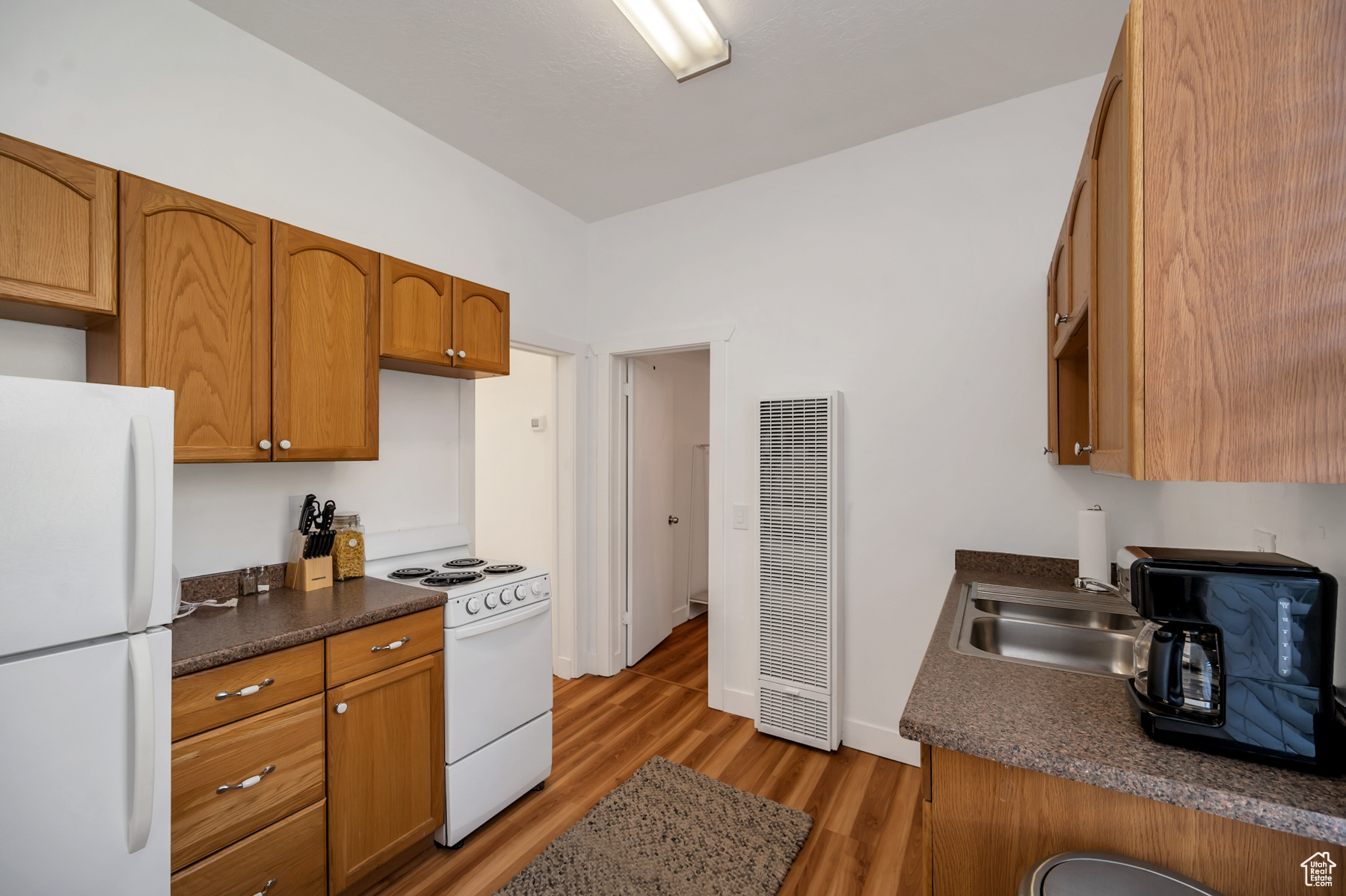 Kitchen with hardwood / wood-style floors, white appliances, and sink