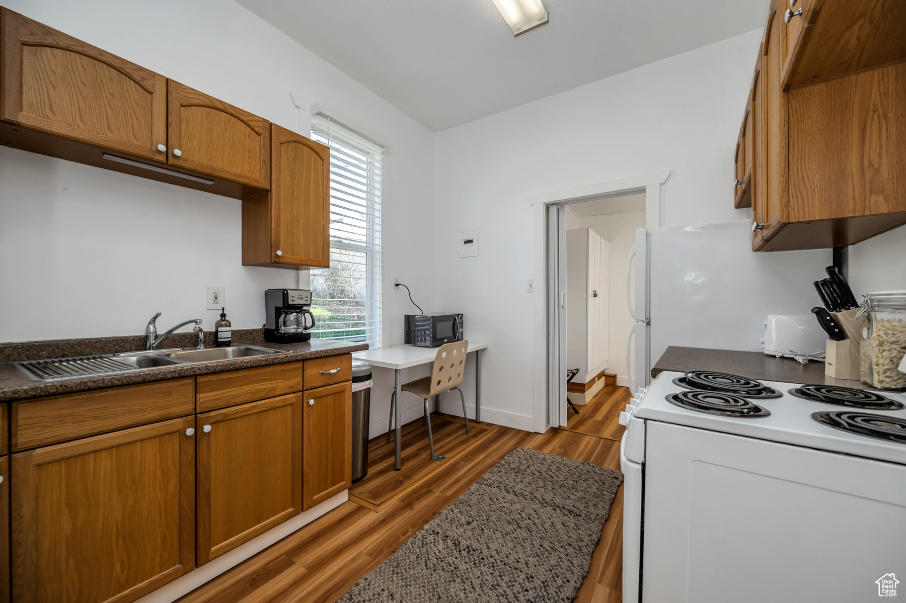 Kitchen with white electric stove, plenty of natural light, sink, and hardwood / wood-style flooring