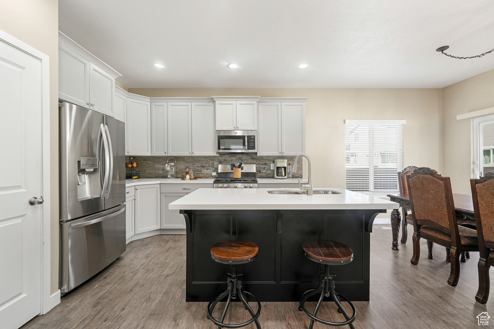 Kitchen featuring wood-type flooring, sink, stainless steel appliances, and white cabinetry