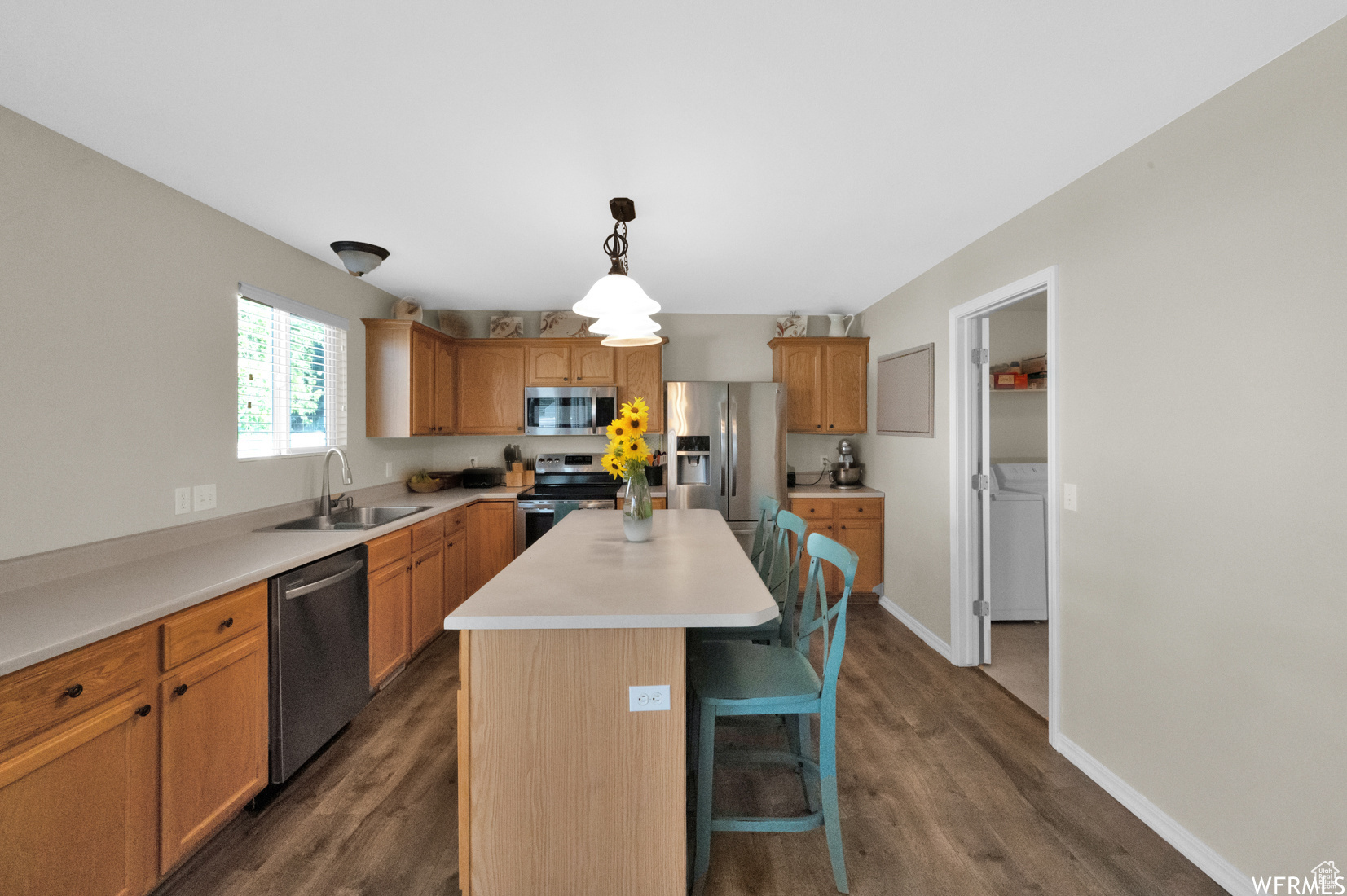 Kitchen featuring a center island, dark wood-type flooring, stainless steel appliances, and sink