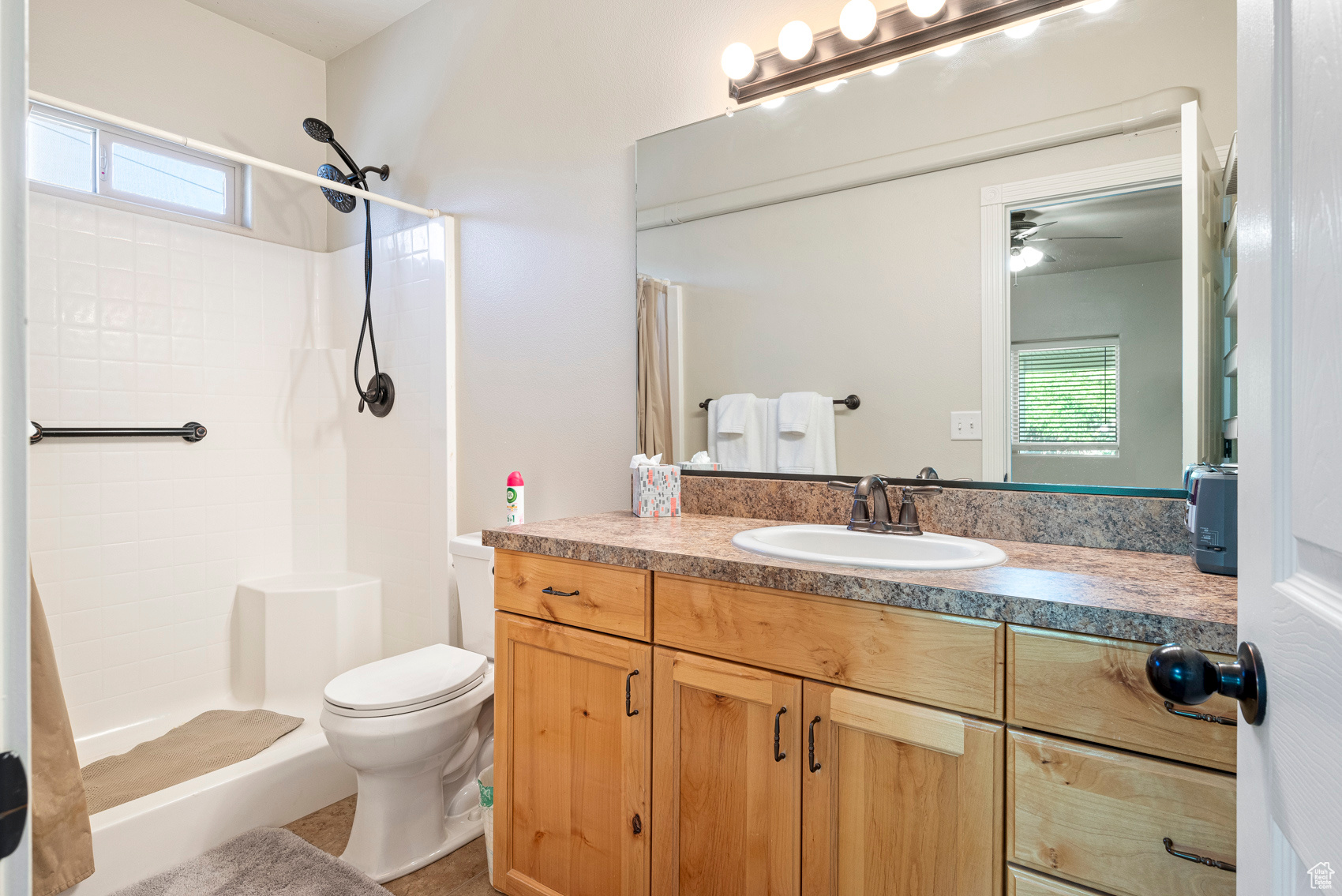 Bathroom with a shower with curtain, ceiling fan, vanity, and toilet