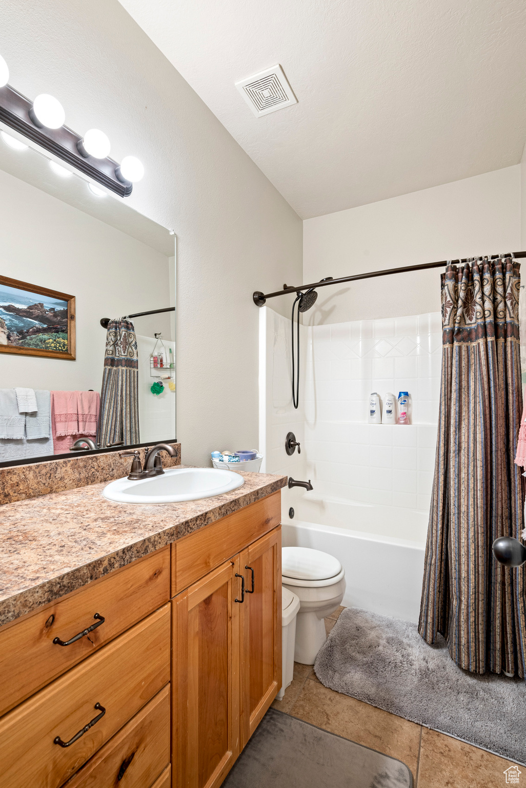 Full bathroom with tile flooring, vanity, toilet, and shower / bath combo with shower curtain