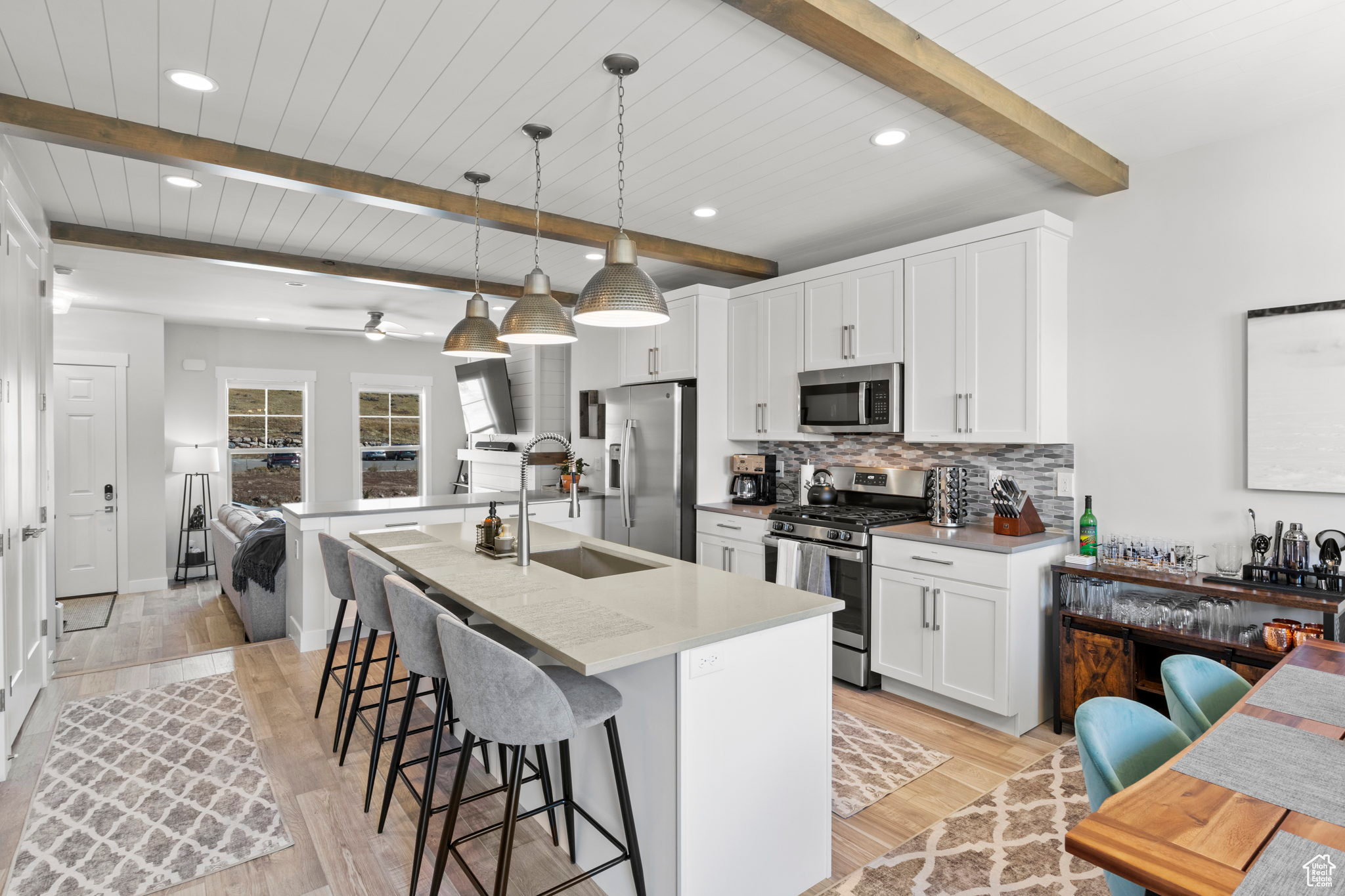 Kitchen with pendant lighting, appliances with stainless steel finishes, beam ceiling, and a kitchen bar