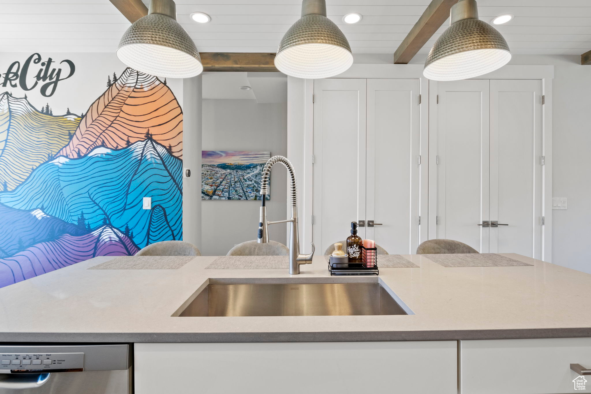 Kitchen featuring a center island, white cabinetry, beam ceiling, sink, and dishwasher
