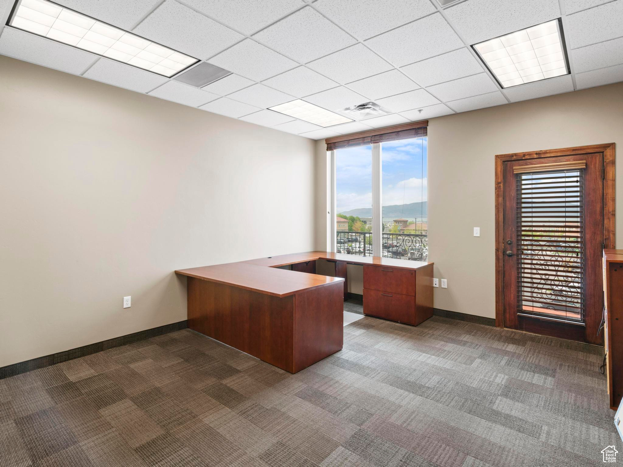 Unfurnished office with a drop ceiling and dark carpet