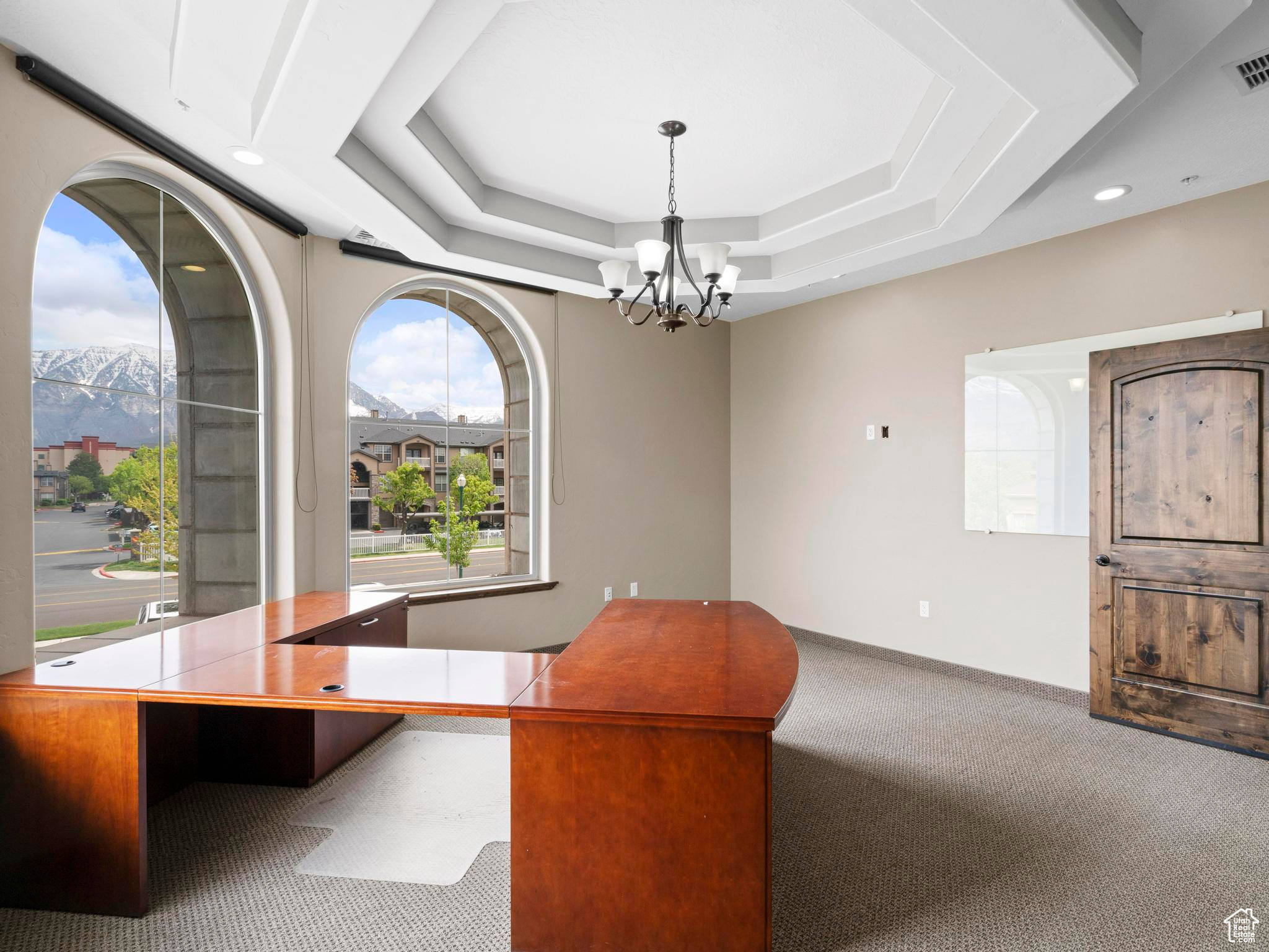 Carpeted office featuring a mountain view, a chandelier, and a tray ceiling