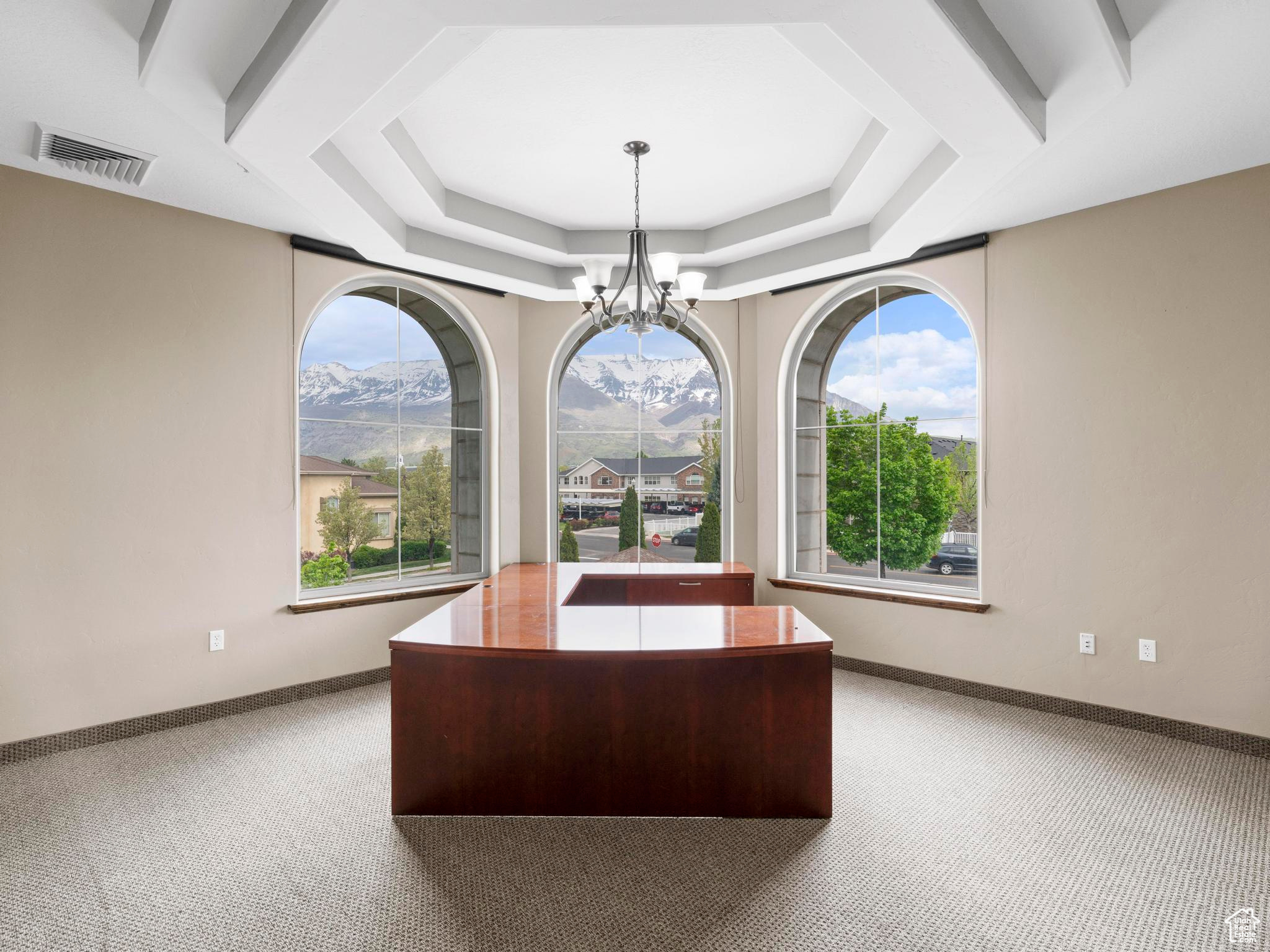 Carpeted home office featuring a mountain view, a chandelier, and a tray ceiling