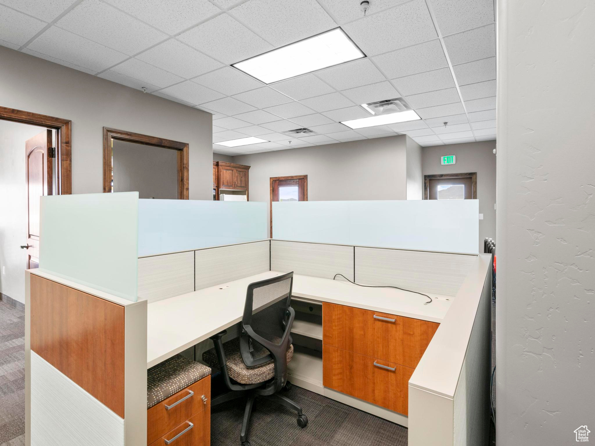 Carpeted home office with a paneled ceiling and built in desk