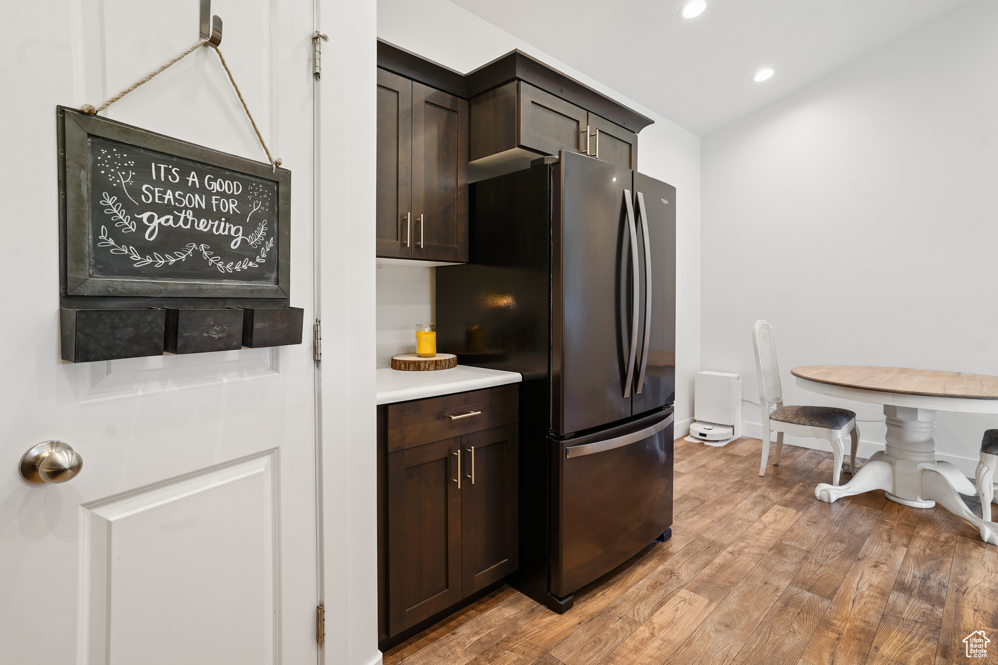 Kitchen featuring dark brown cabinetry, refrigerator, and light hardwood / wood-style floors