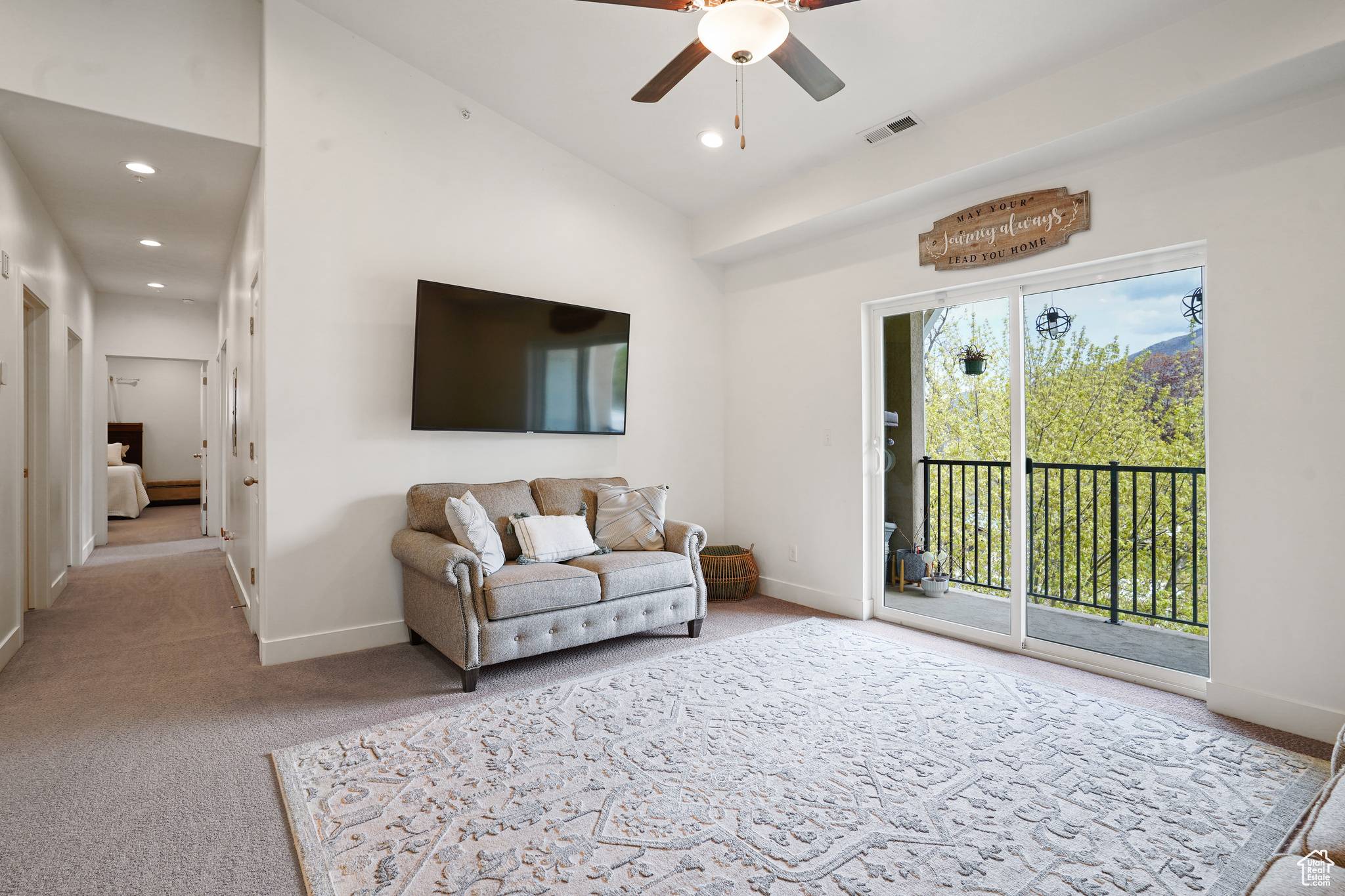 Carpeted living room with high vaulted ceiling and ceiling fan