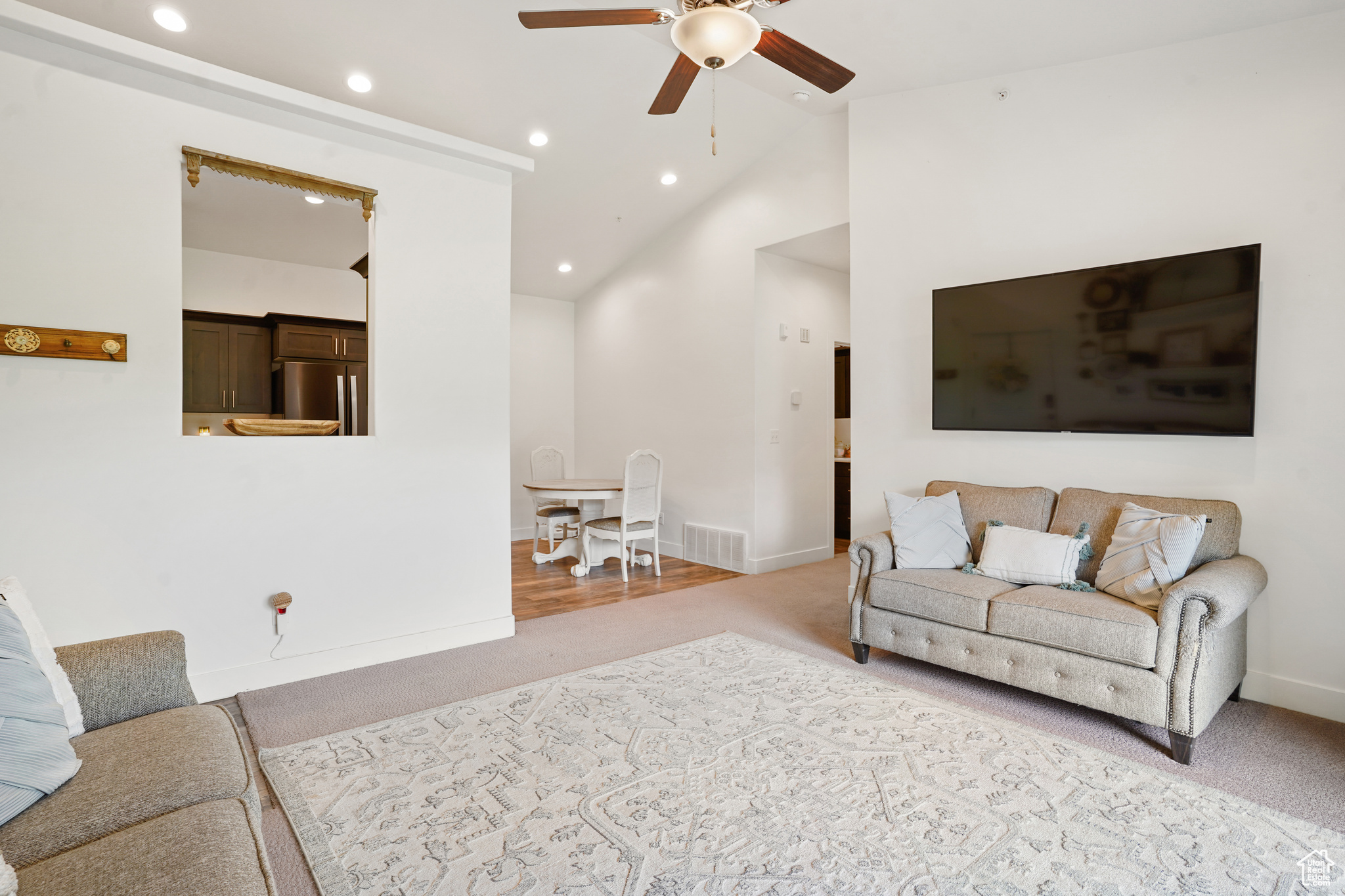 Carpeted living room featuring high vaulted ceiling and ceiling fan