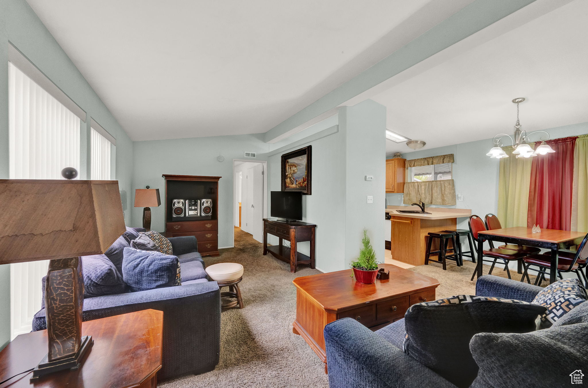 Carpeted living room with lofted ceiling, sink, and an inviting chandelier