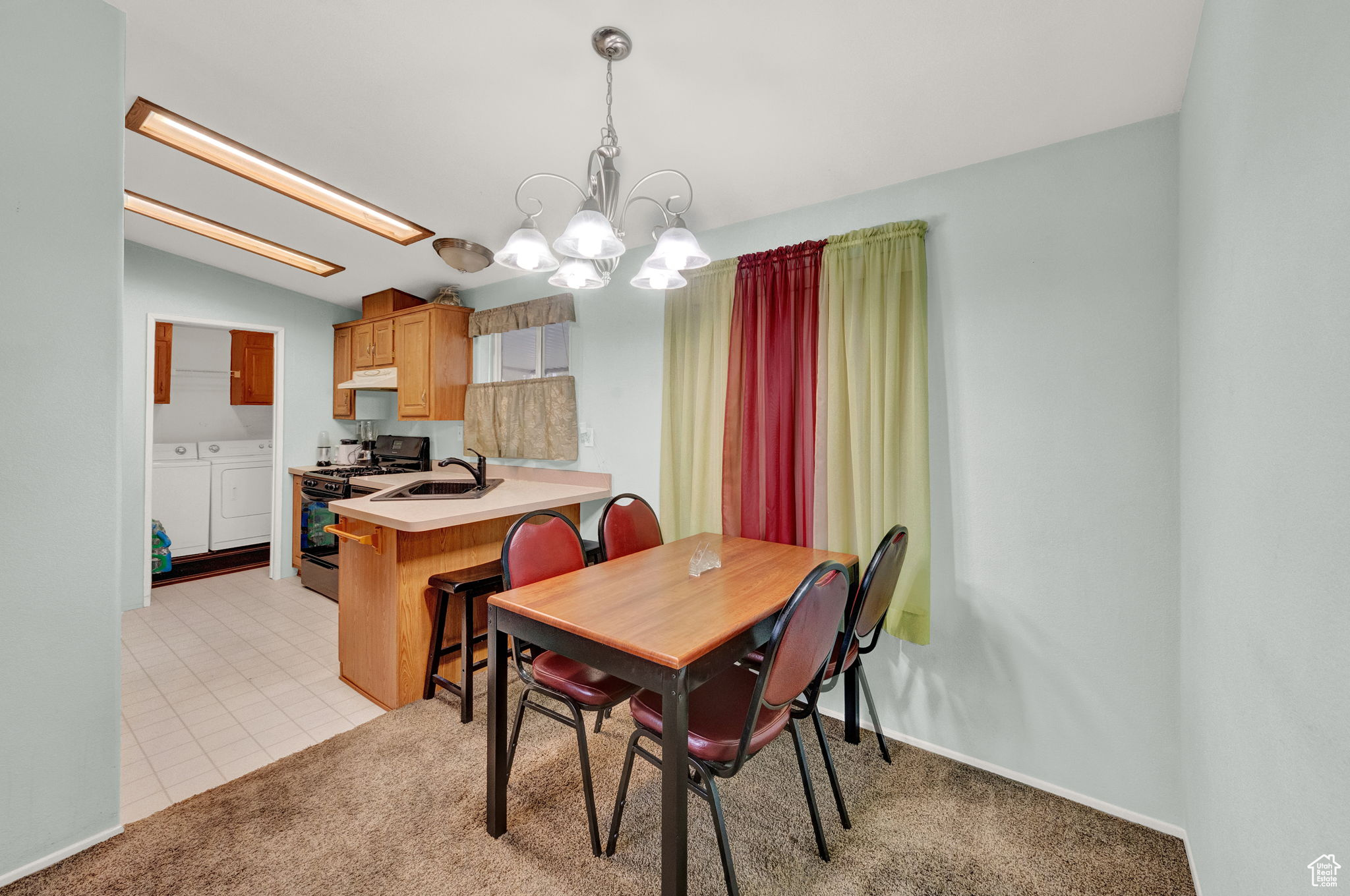 Tiled dining space featuring sink, independent washer and dryer, and an inviting chandelier