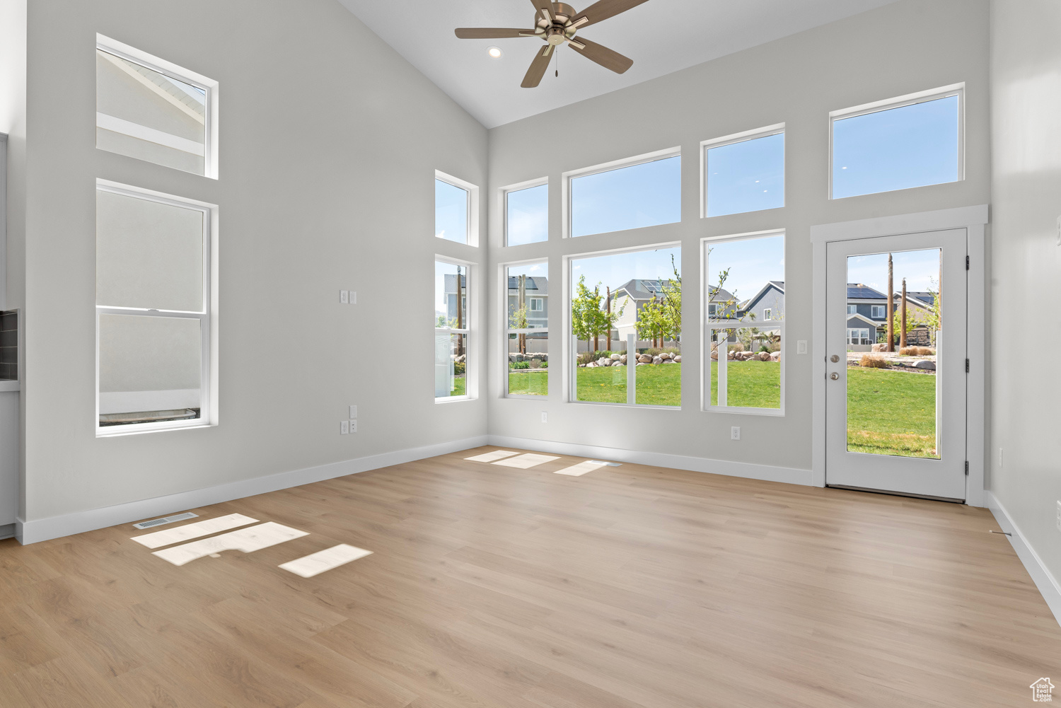 Unfurnished sunroom featuring lofted ceiling, a wealth of natural light, and ceiling fan