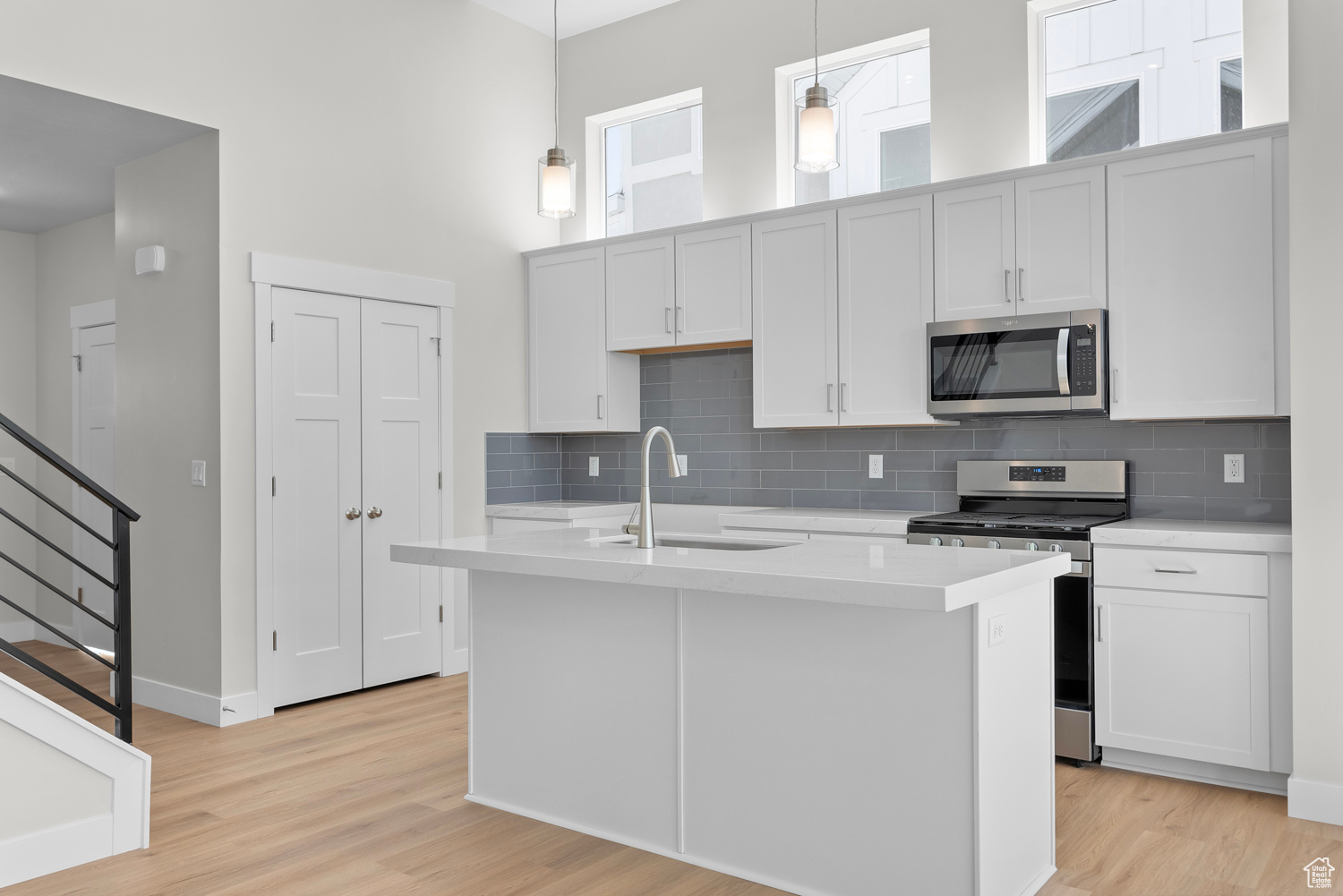 Kitchen with appliances with stainless steel finishes, sink, pendant lighting, and light hardwood / wood-style floors