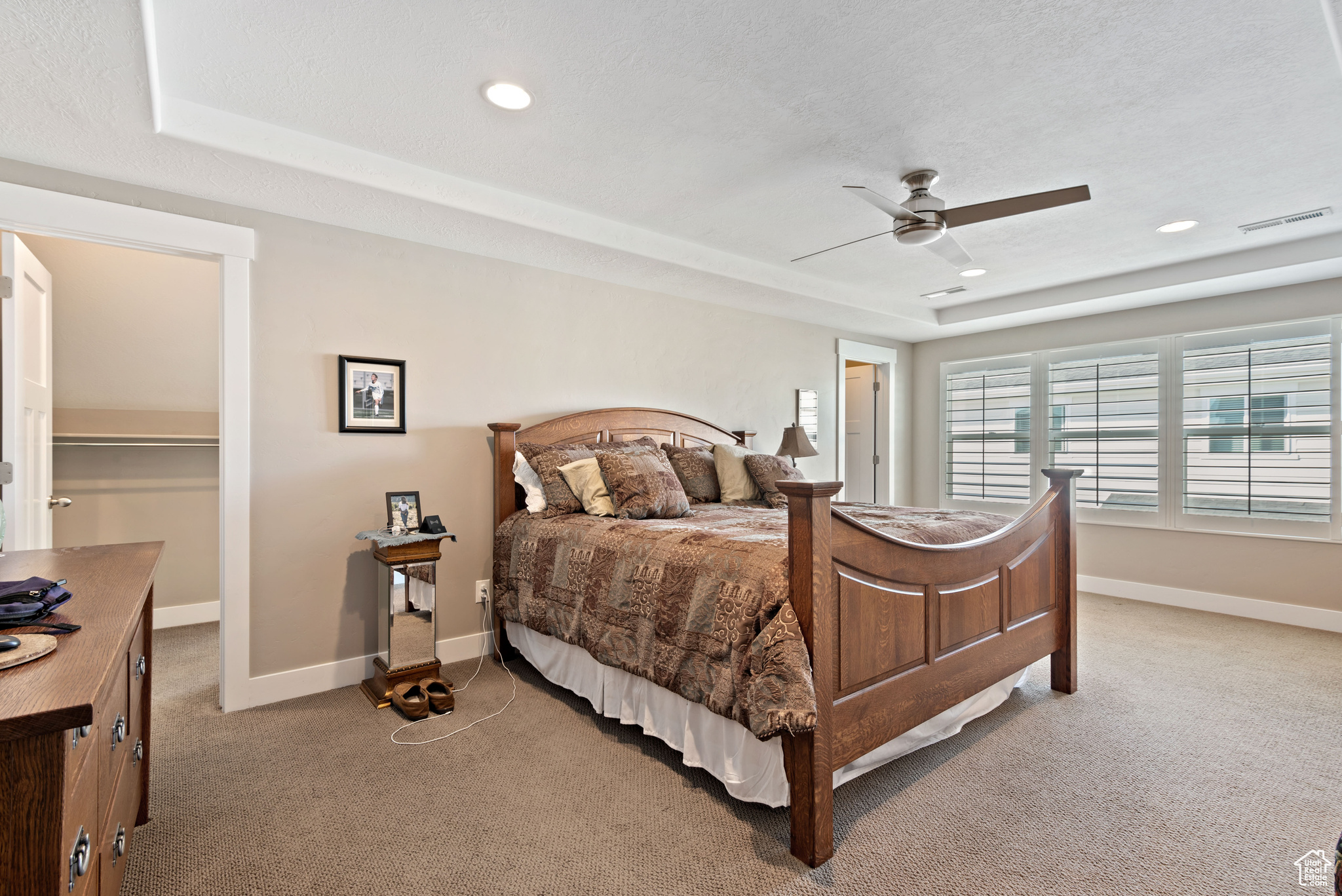 Carpeted bedroom featuring a closet, a spacious closet, ceiling fan, and a tray ceiling