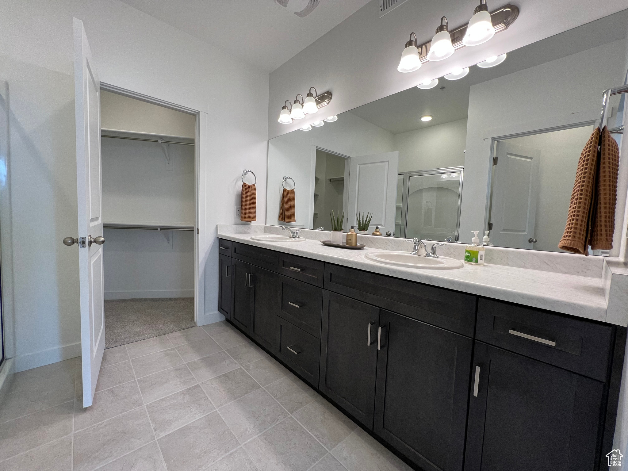 Bathroom with dual sinks, tile floors, and large vanity