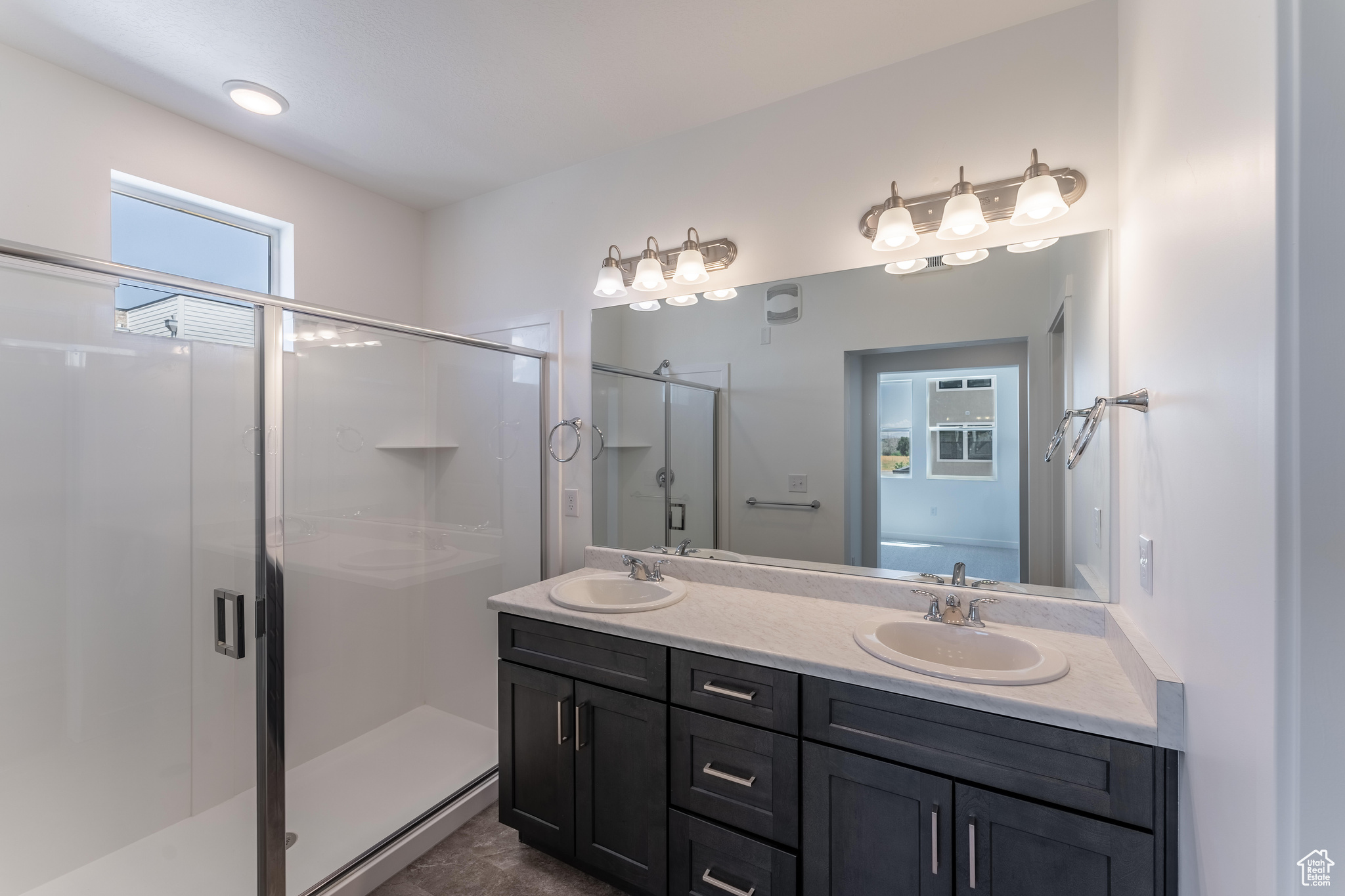 Bathroom featuring dual sinks, oversized vanity, walk in shower, and tile flooring