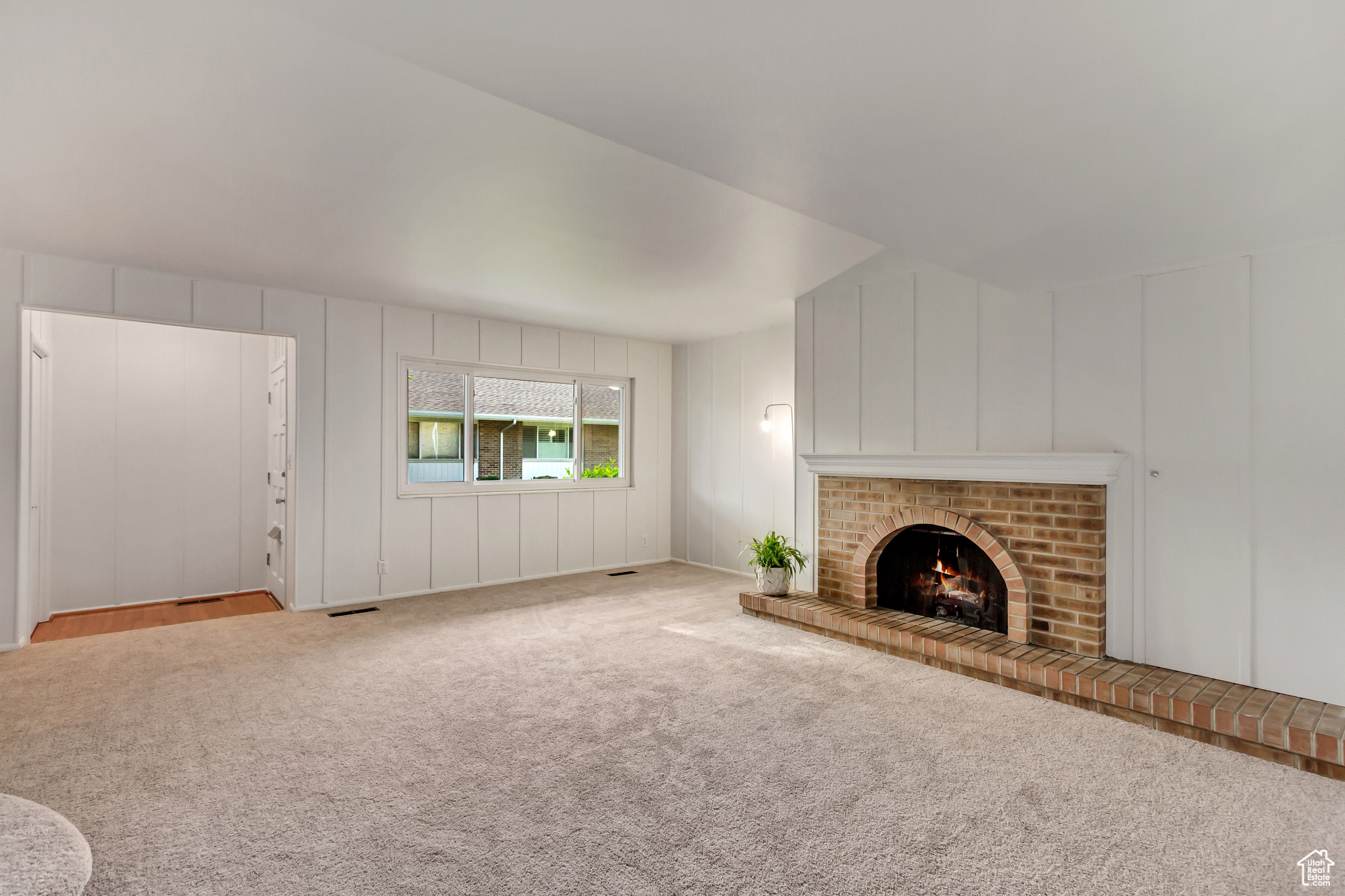 Unfurnished living room featuring light colored carpet and a fireplace