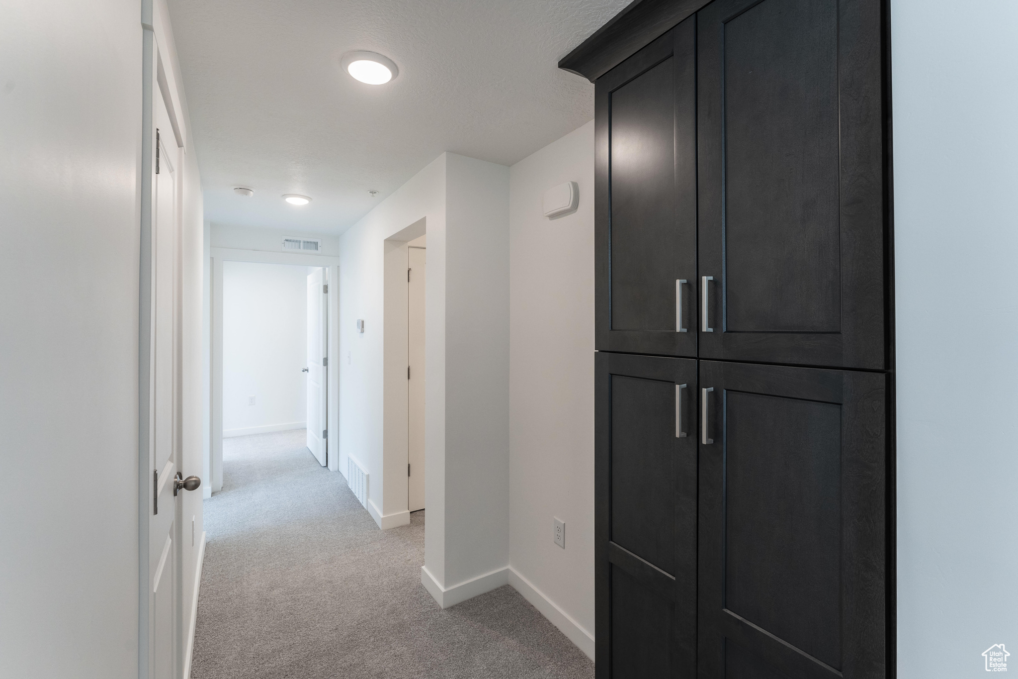 Hallway featuring light colored carpet