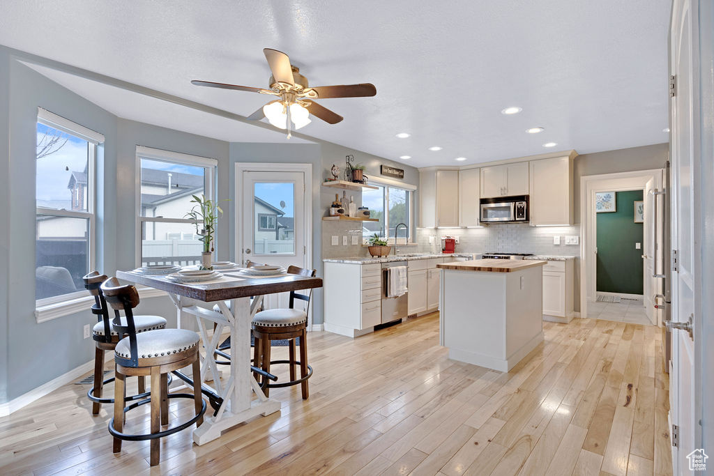 Kitchen with a center island, ceiling fan, backsplash, and light wood-type flooring