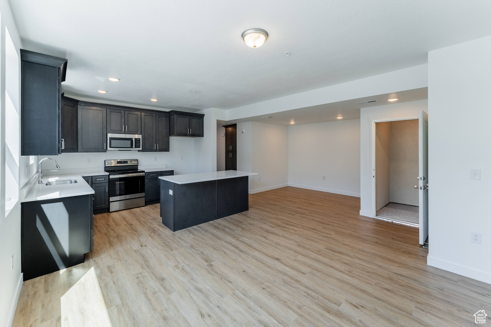Kitchen with a center island, light hardwood / wood-style flooring, stainless steel appliances, and sink