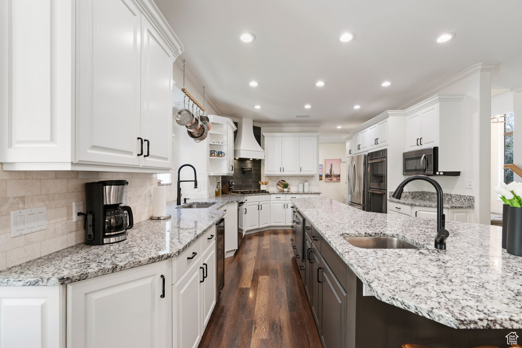 Kitchen featuring appliances with stainless steel finishes, sink, white cabinetry, dark hardwood / wood-style floors, and premium range hood