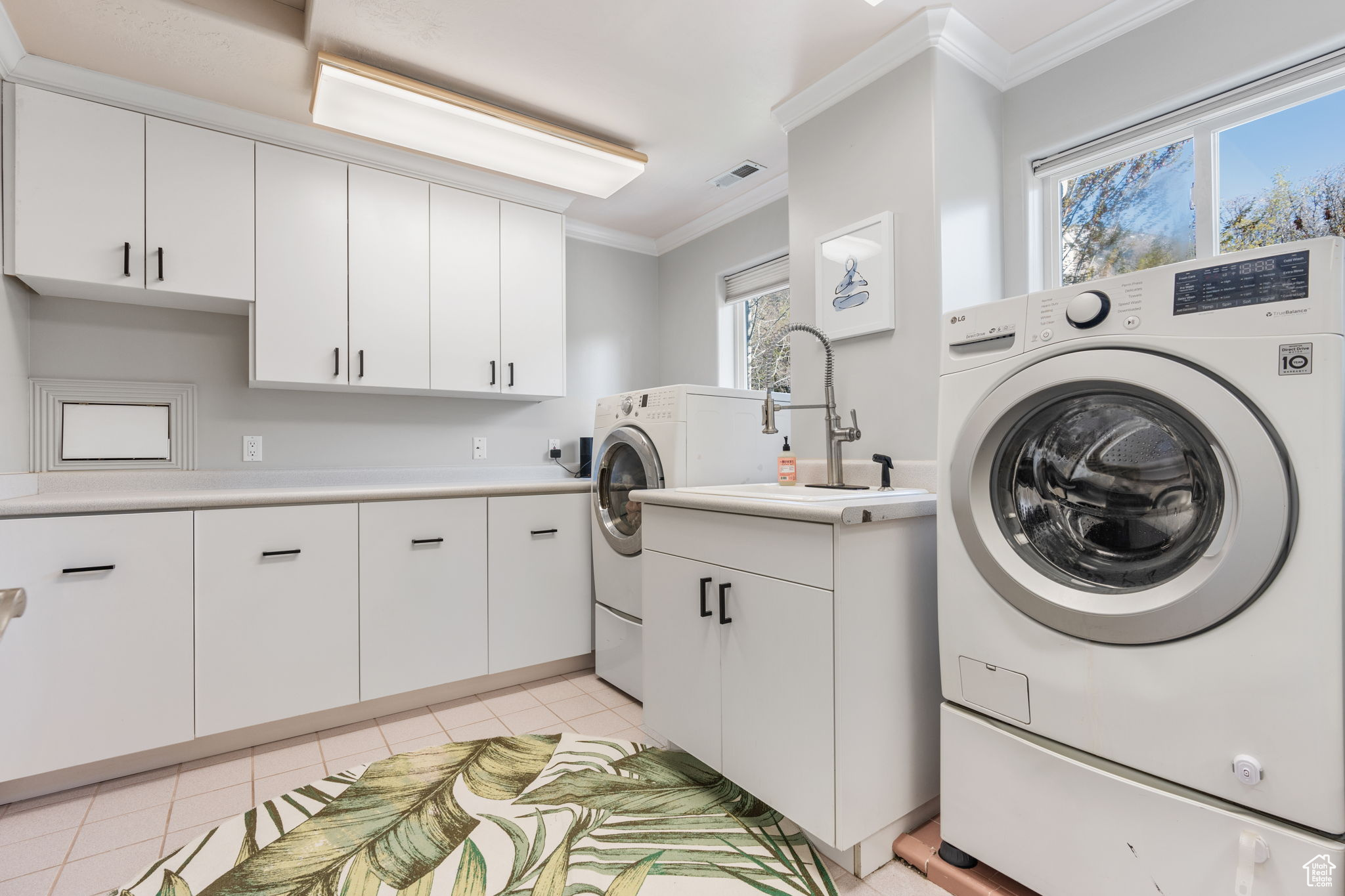 Clothes washing area featuring cabinets, light tile floors, sink, and washer and clothes dryer