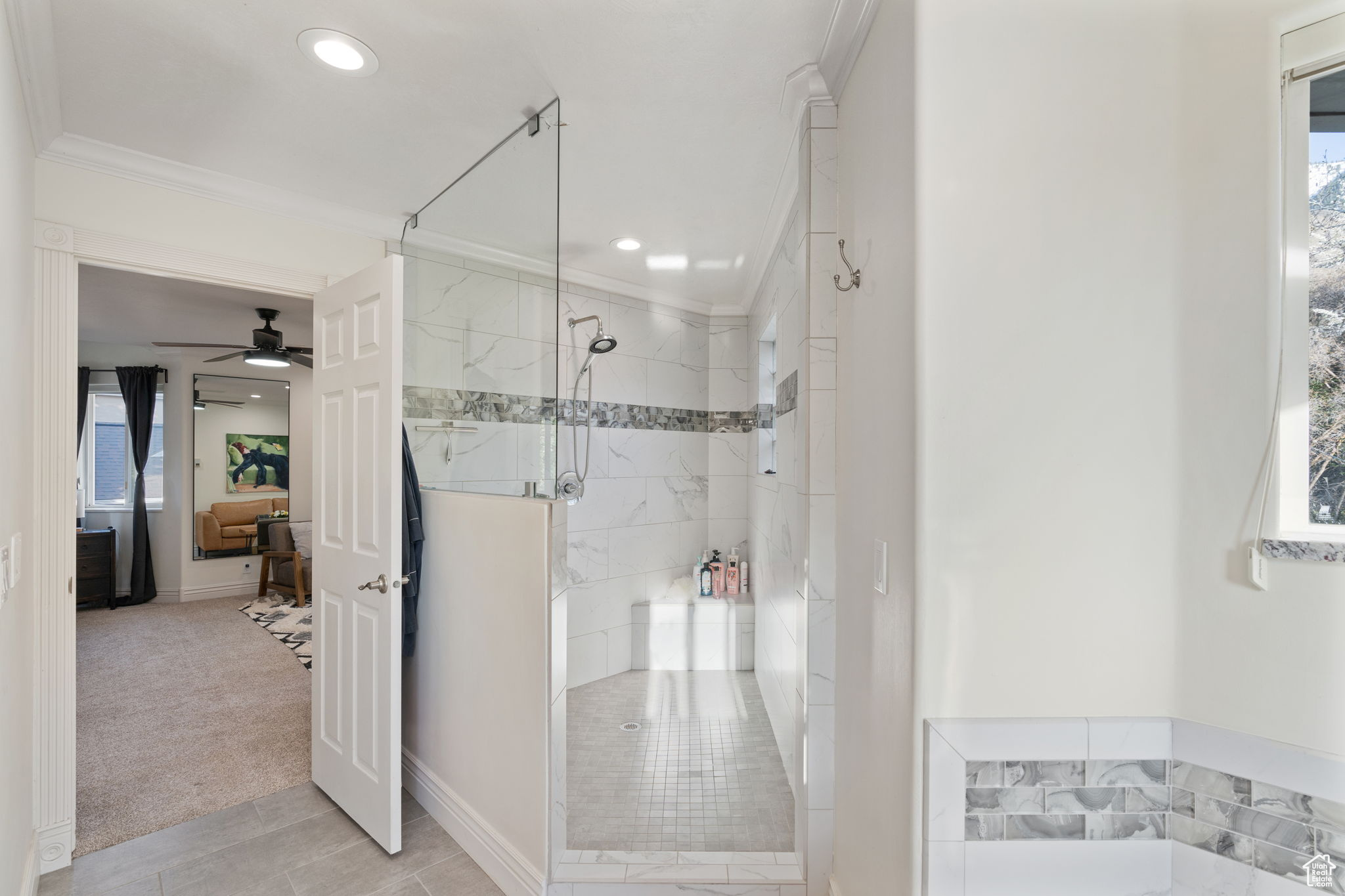 Bathroom featuring ornamental molding, tile flooring, ceiling fan, and a tile shower