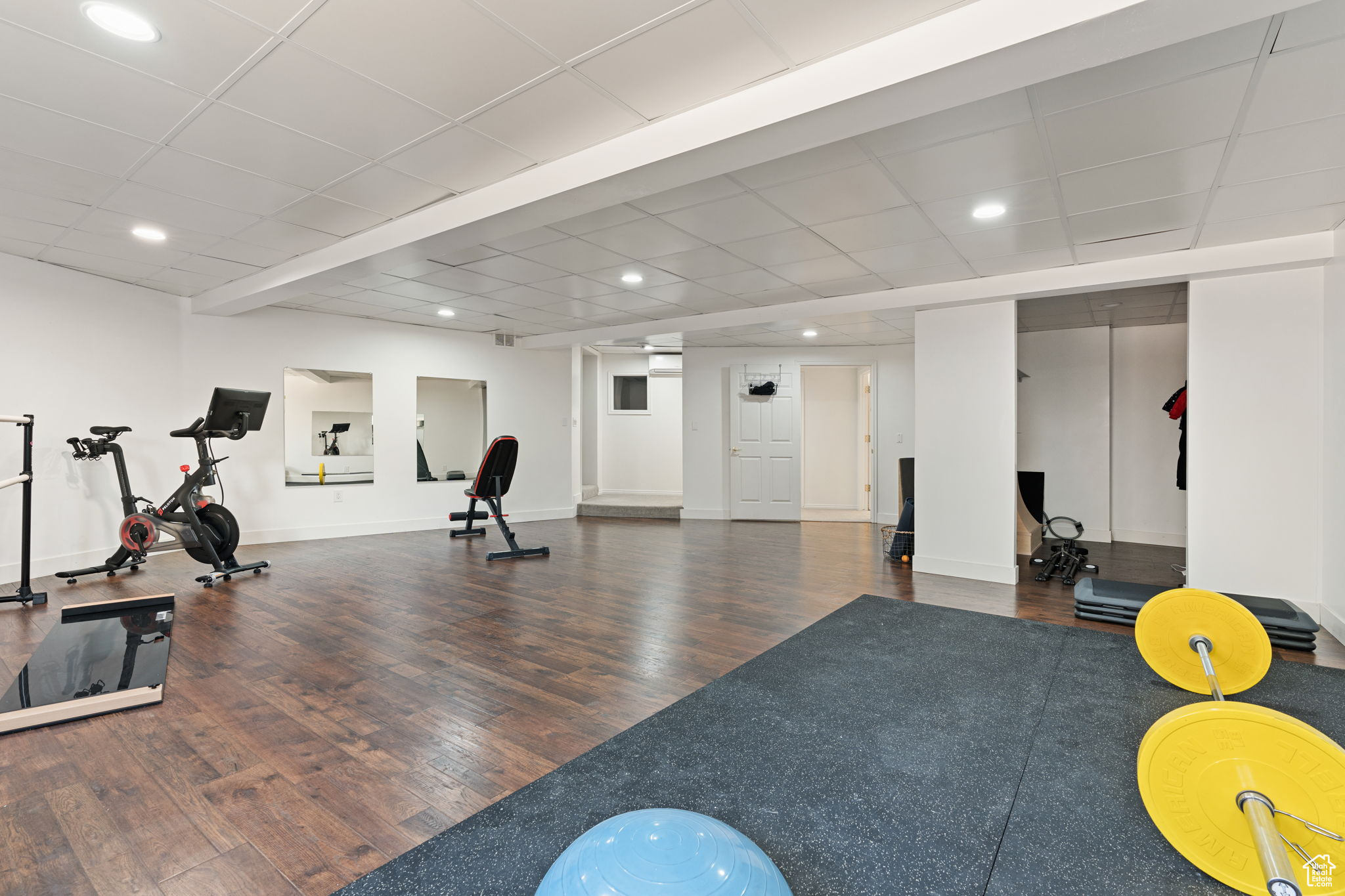 Exercise room with a drop ceiling and hardwood / wood-style flooring