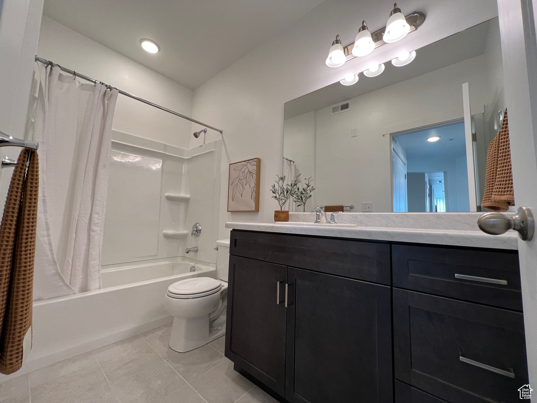 Full bathroom with tile floors, vanity, toilet, and shower / bath combo with shower curtain