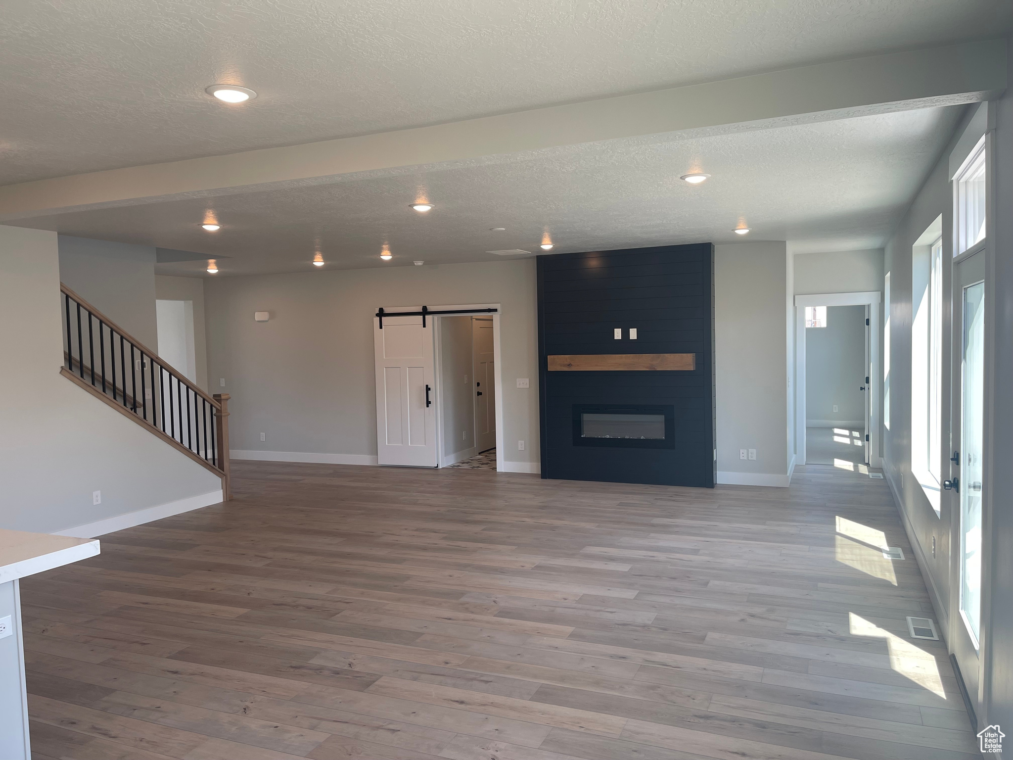 Unfurnished living room with a barn door, a textured ceiling, hardwood / wood-style floors, and a fireplace